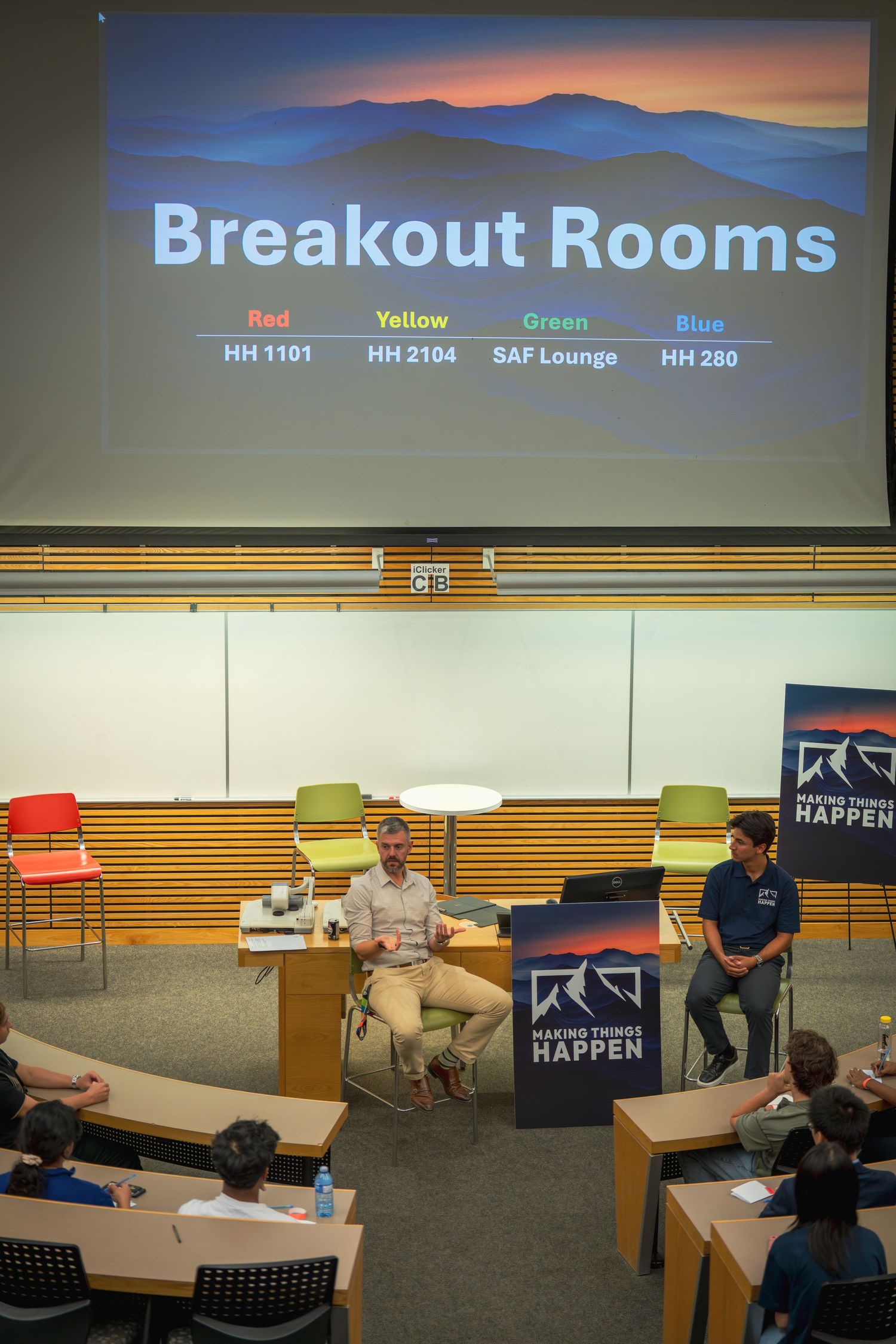 Conference room with breakout session signage showing color-coded room assignments and mountain backdrop.