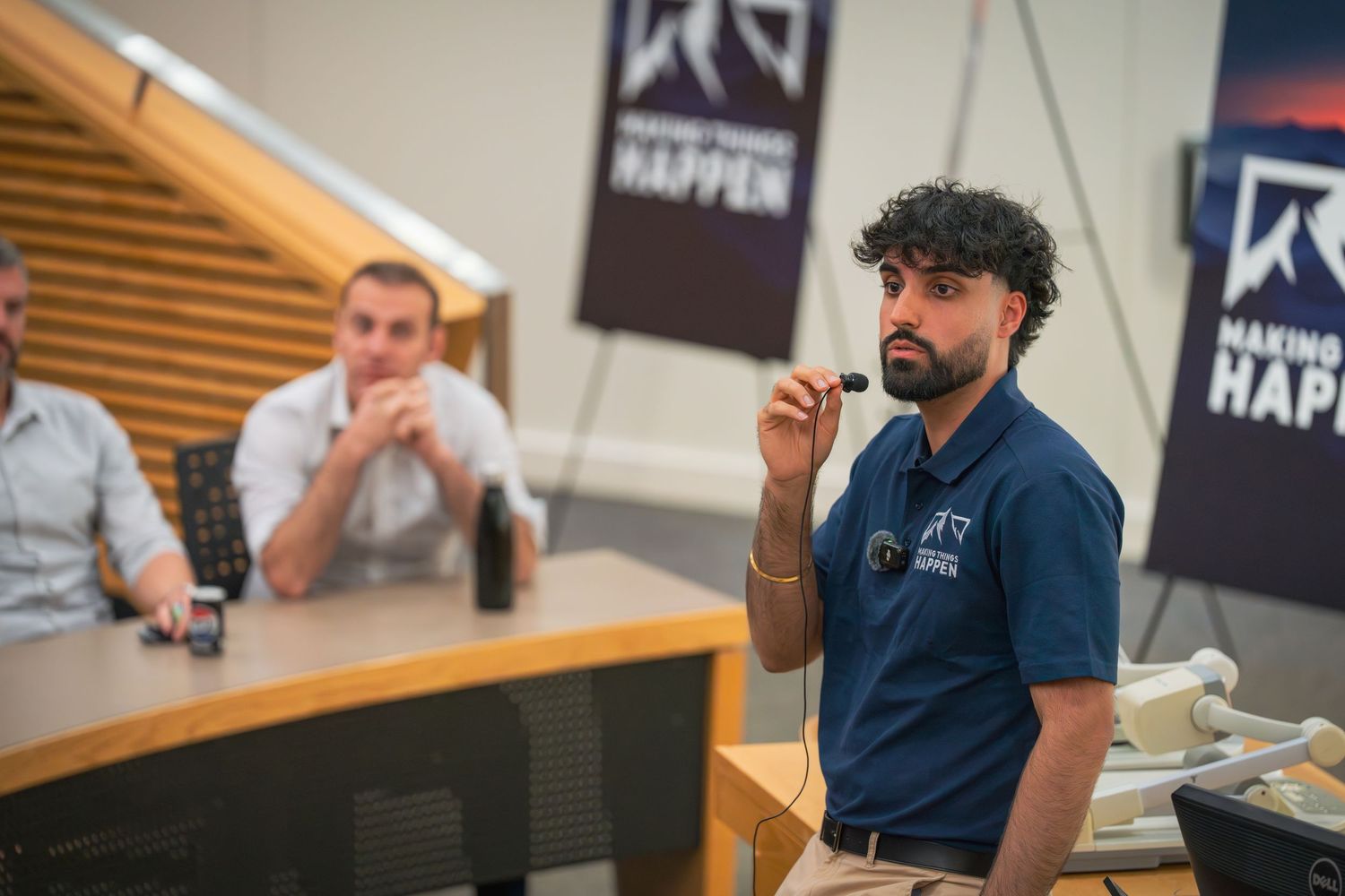 Business meeting participants engage in discussion in modern conference space with branded signage.