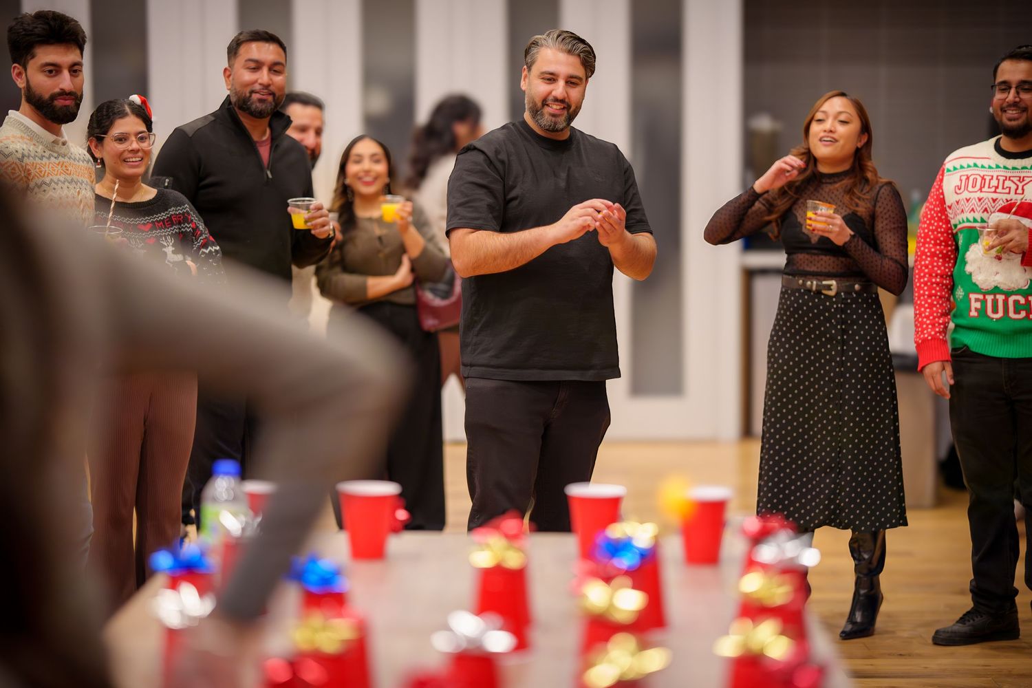 People playing a party game with red cups on the floor at an indoor event.