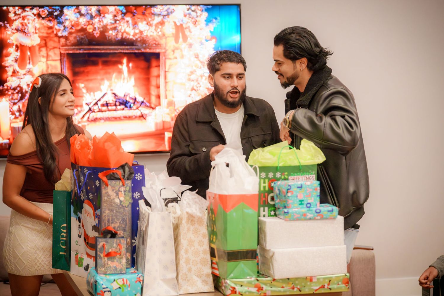 Group celebrating around wrapped presents and decorations at indoor gathering.