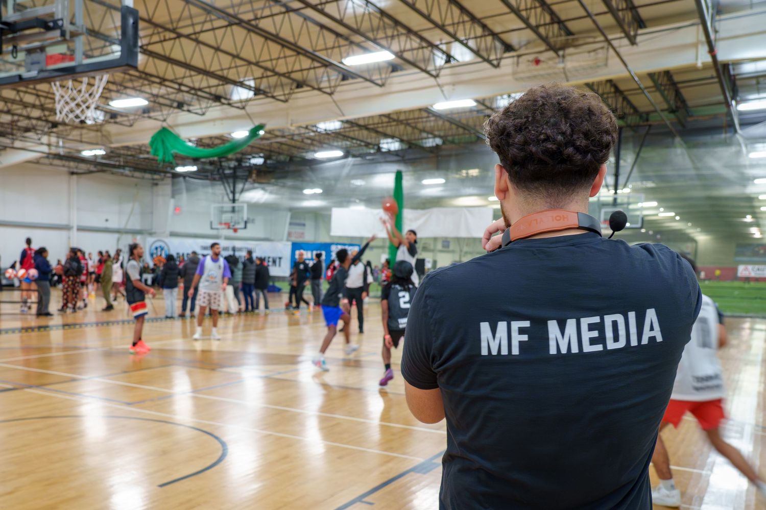 Basketball players and spectators gather in a large indoor gymnasium during a sports event.