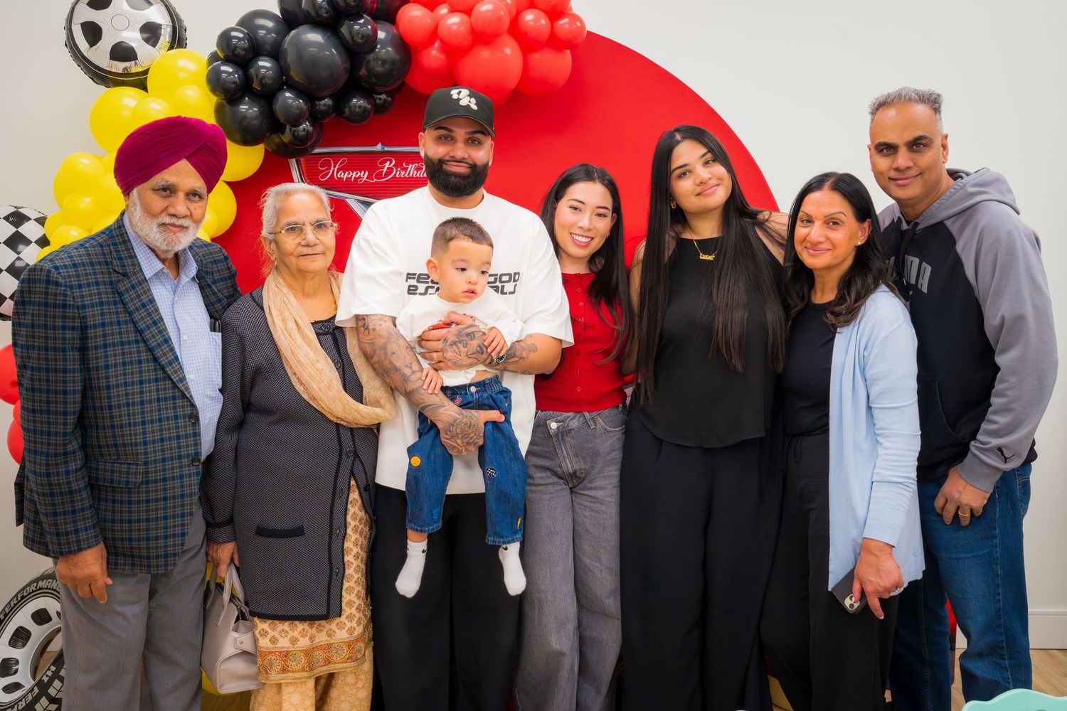 Multi-generational family posing together at a Happy Birthday racing themed celebration party.