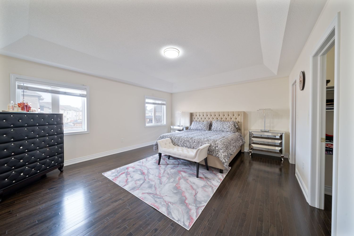 Modern white hallway with recessed lighting, hardwood floors, and floral accent pillows on built-in seating.