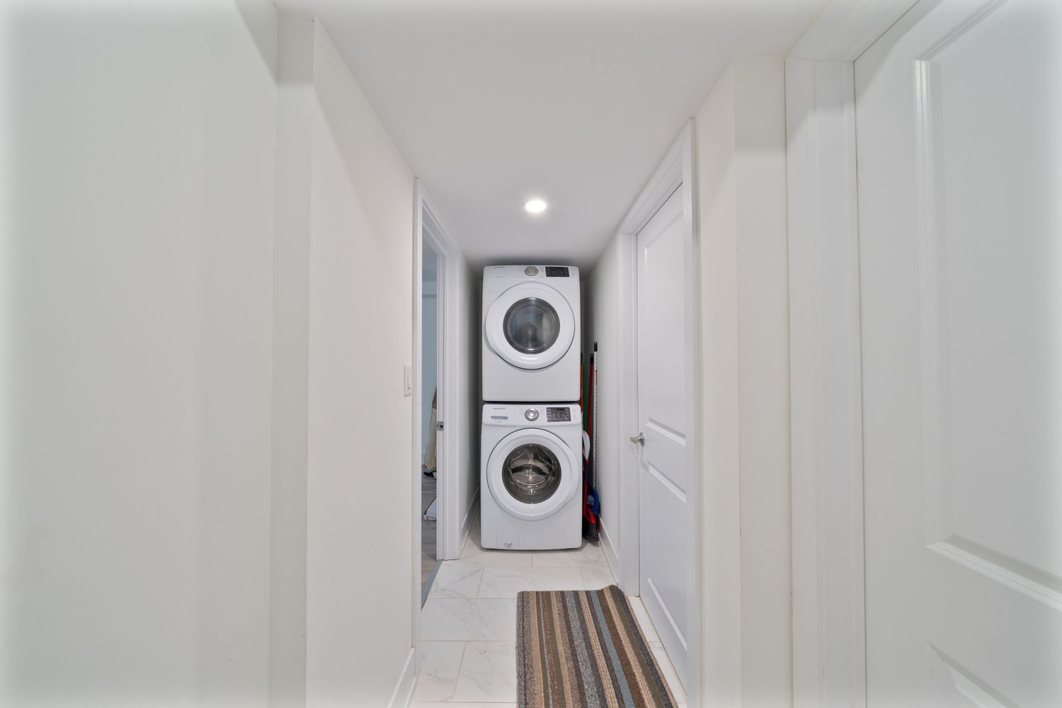 Long white hallway with modern light fixtures and wooden flooring leading to a bright end.