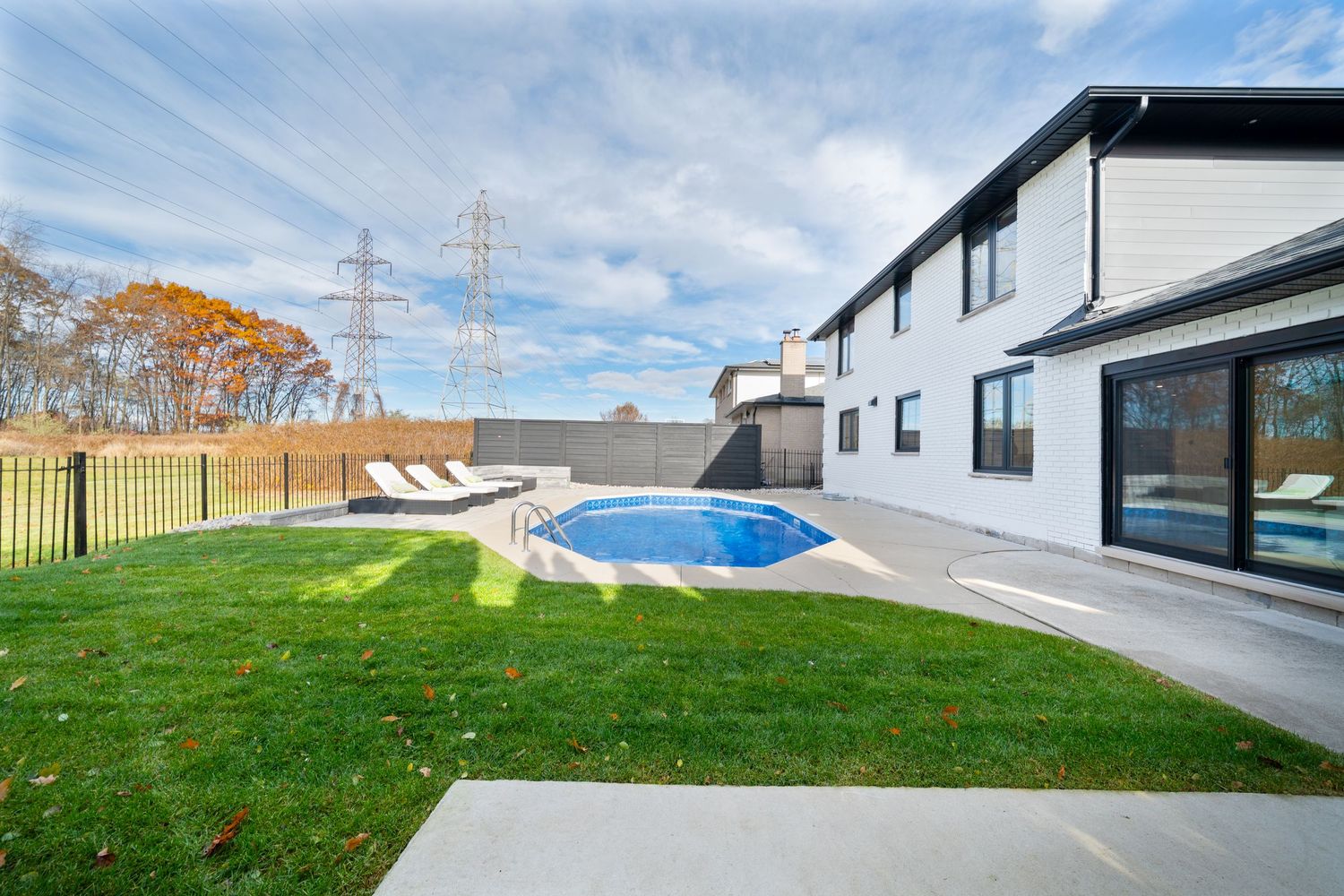 A modern residential property with a sloped green lawn and minimalist architectural design against a bright blue sky.