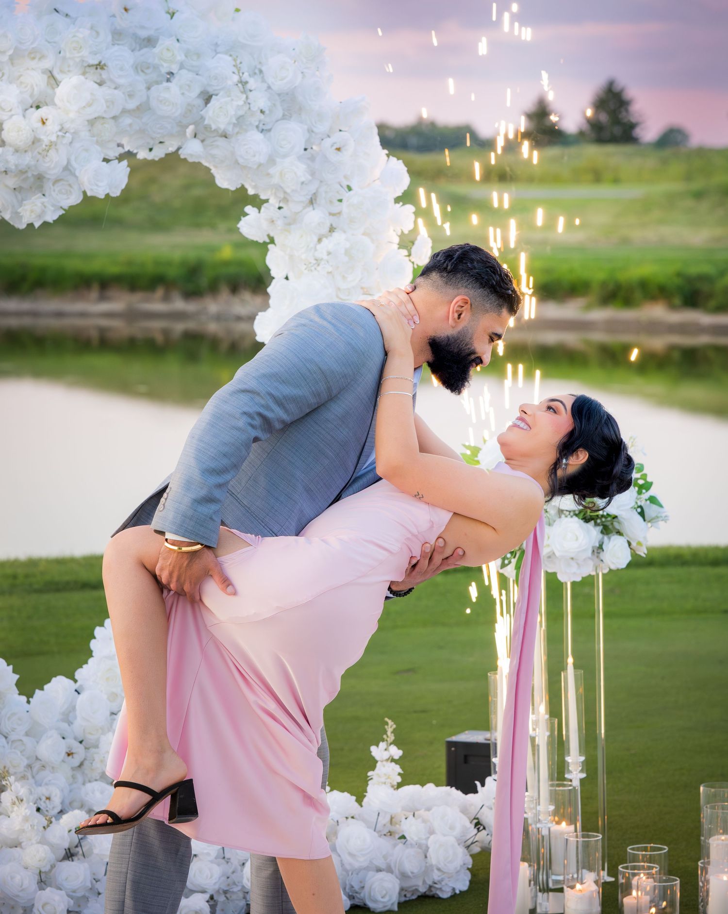 A dramatic dip pose captured during sunset with white floral arch and candlelight.