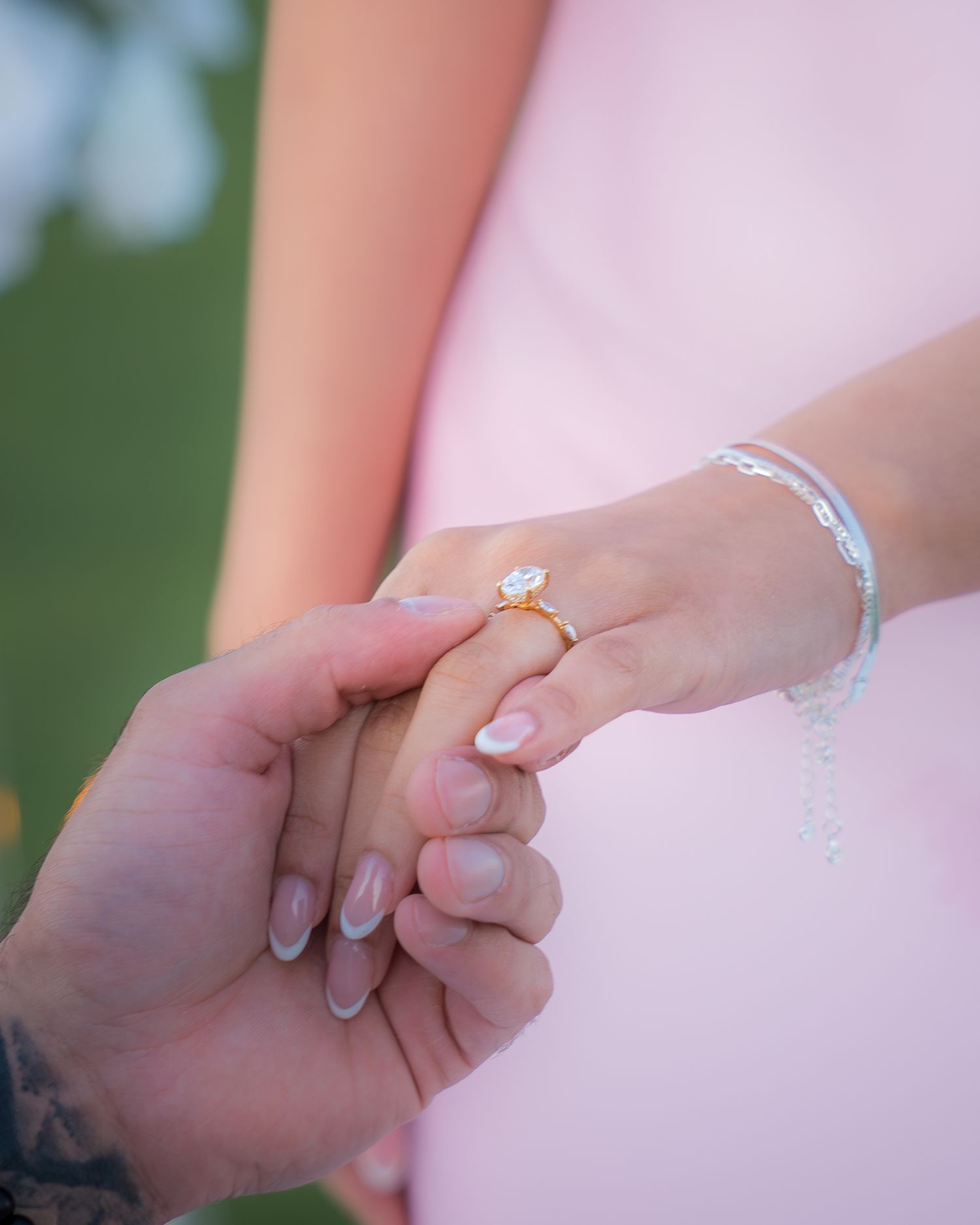 Close-up of hands with engagement ring during romantic outdoor proposal.