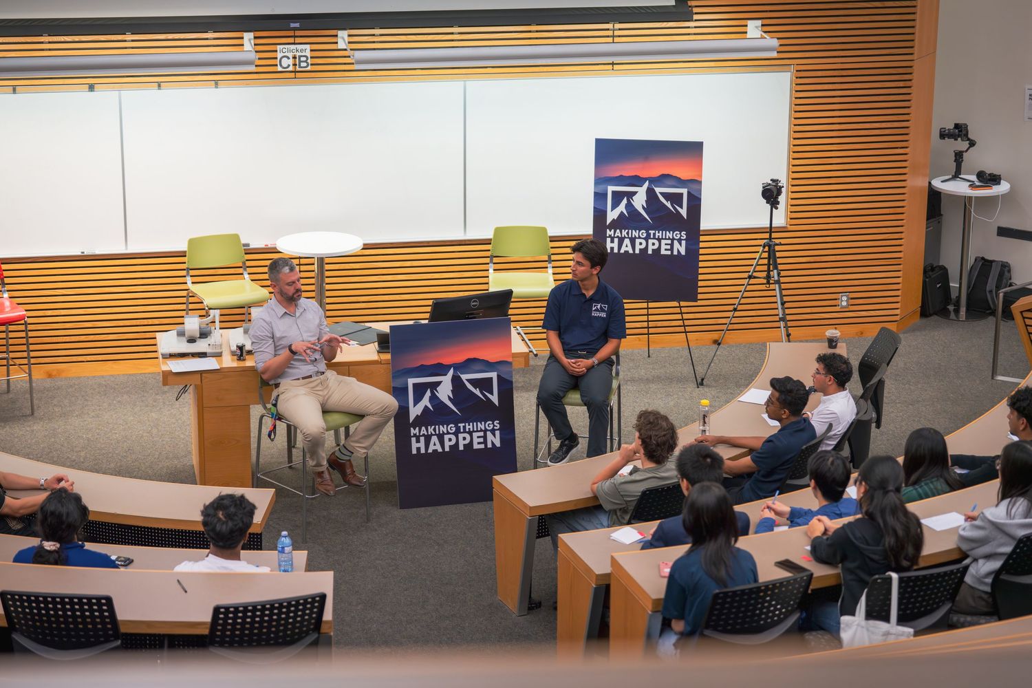 Panoramic view of classroom with students and presentation displays visible.