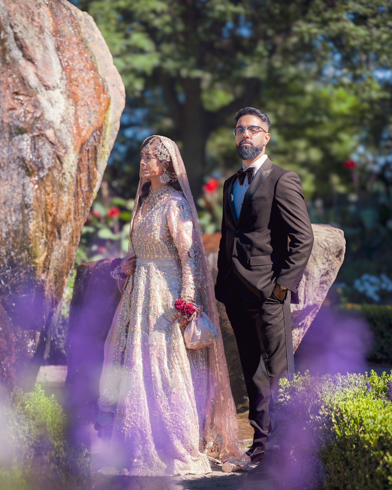 A wedding portrait with artistic purple lighting effects captured in a garden setting.