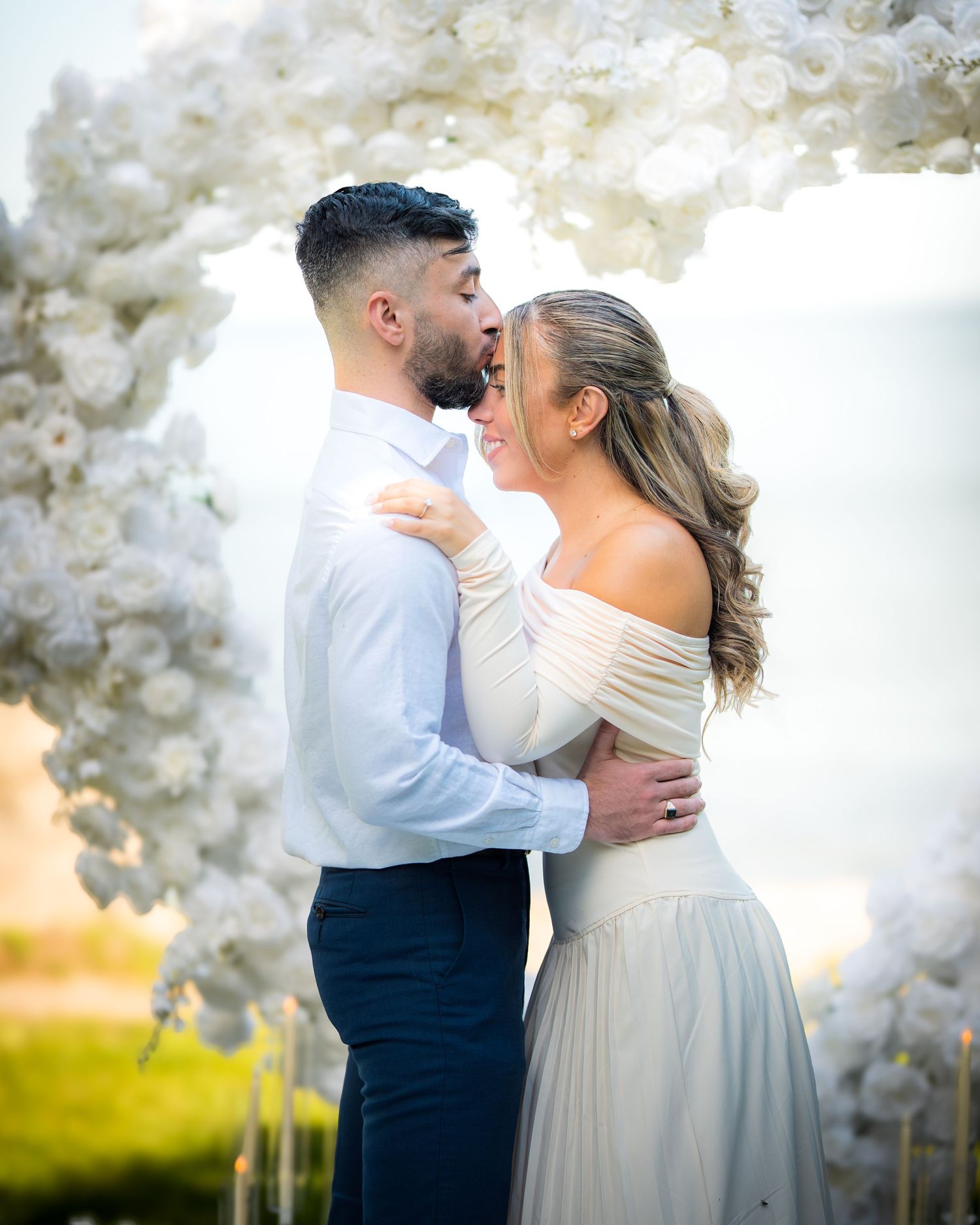 Couple embracing during their first dance under white floral decorations.