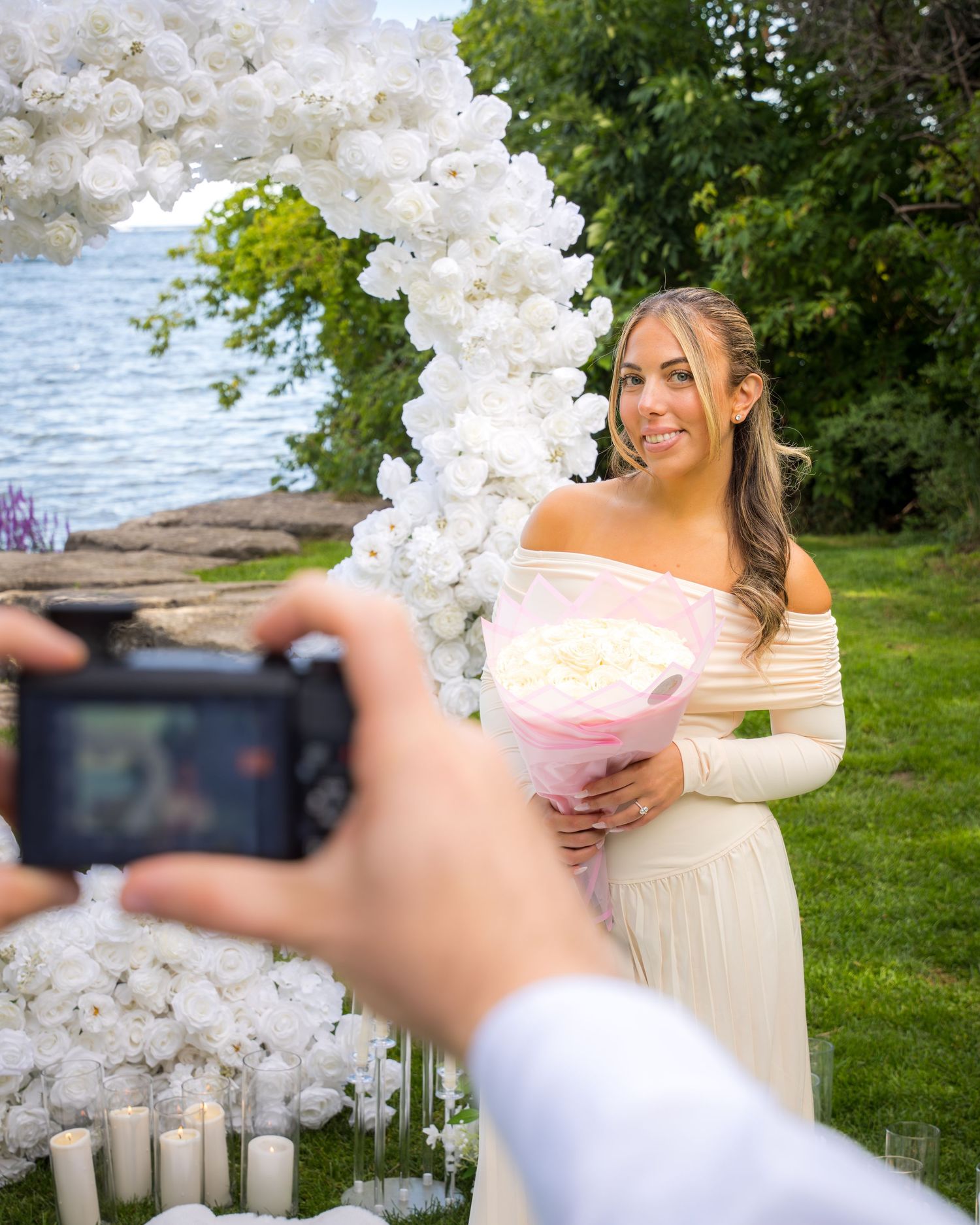 Behind-the-scenes photo of capturing a romantic proposal moment under a floral arch.