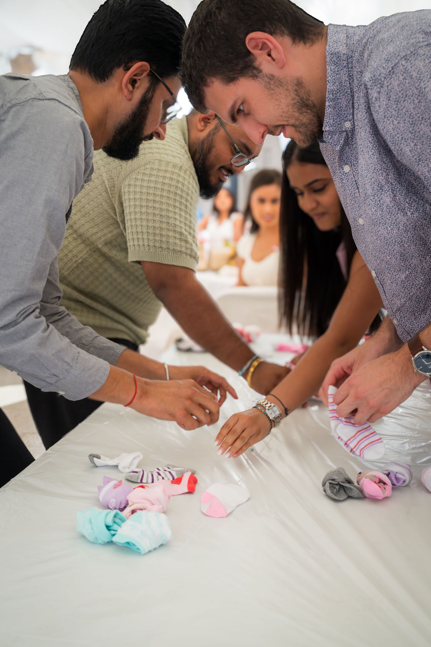 Multiple guests leaning over a table playing a baby shower game.