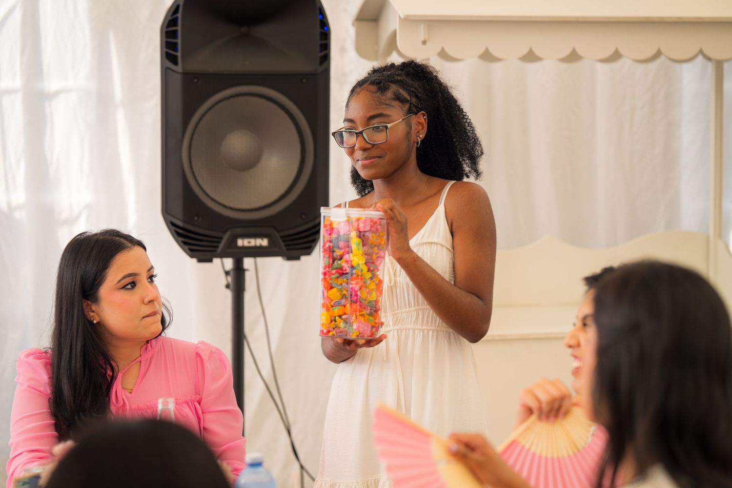 Party guests engaged in conversation and activities at a pink-themed celebration.