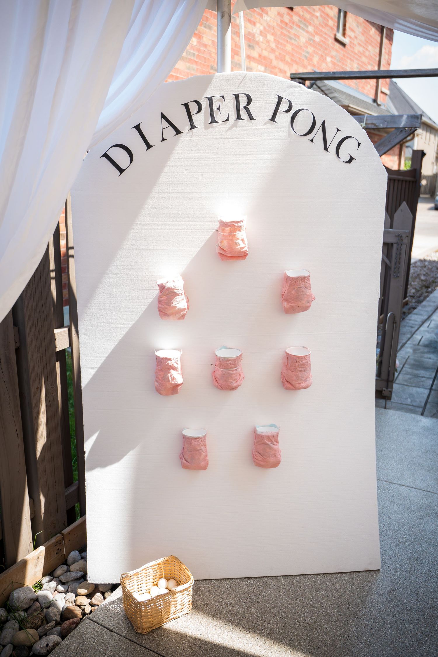 Paper pong game setup with pink cups arranged on a white backdrop wall.