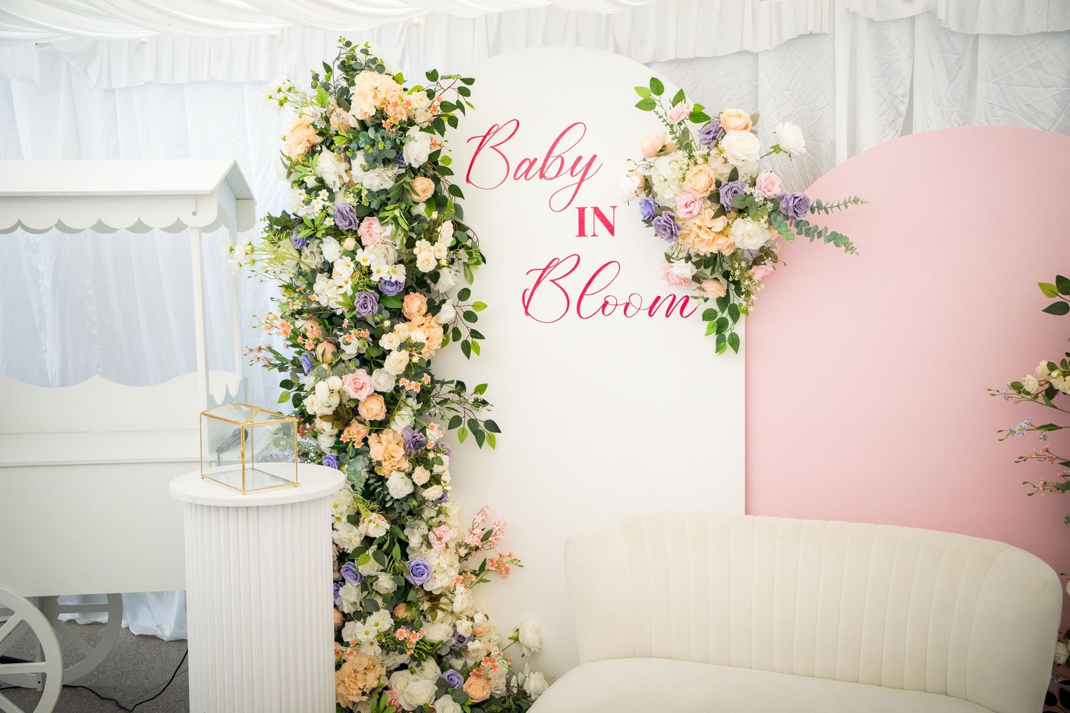 White and pink floral arrangement with 'Baby' text displayed on elegant backdrop for celebration.
