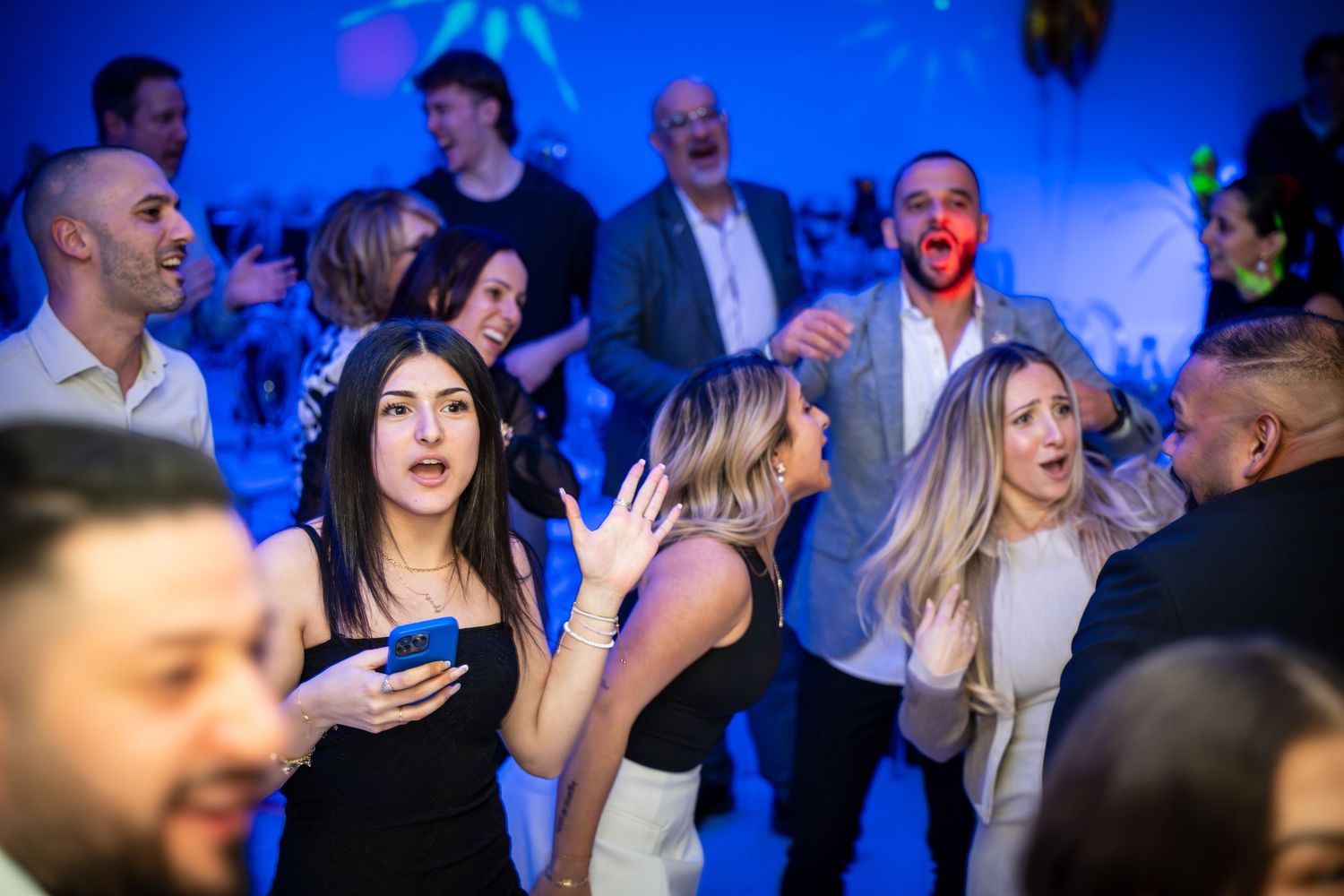Candid shot of party guests dancing and socializing under blue ambient lighting.