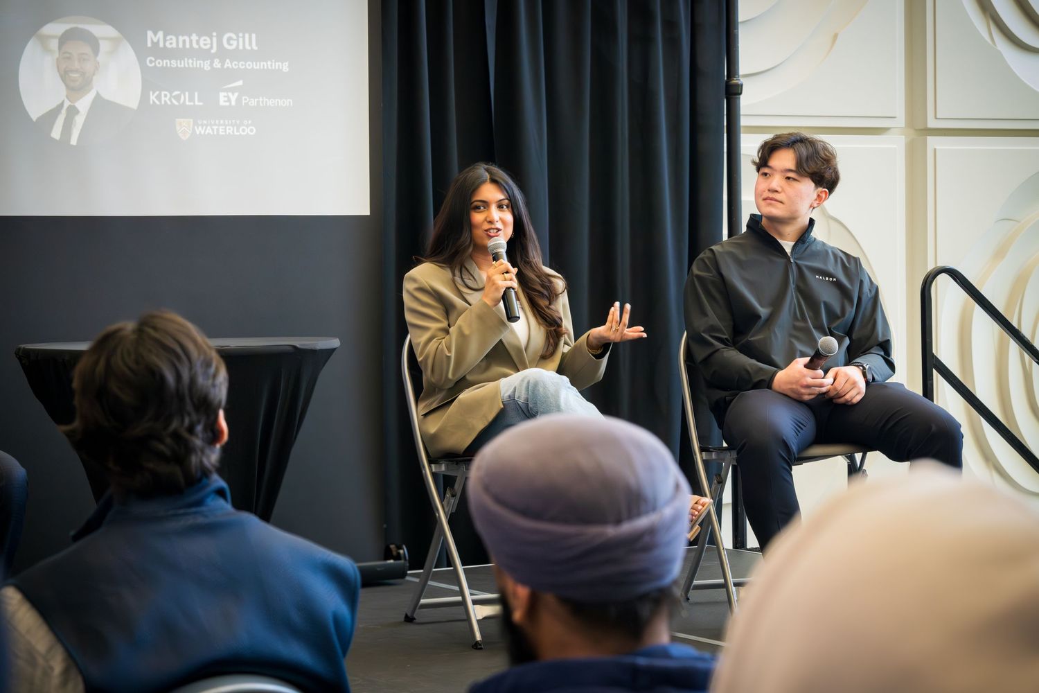 Professional speakers engage in animated discussion during staged panel event.
