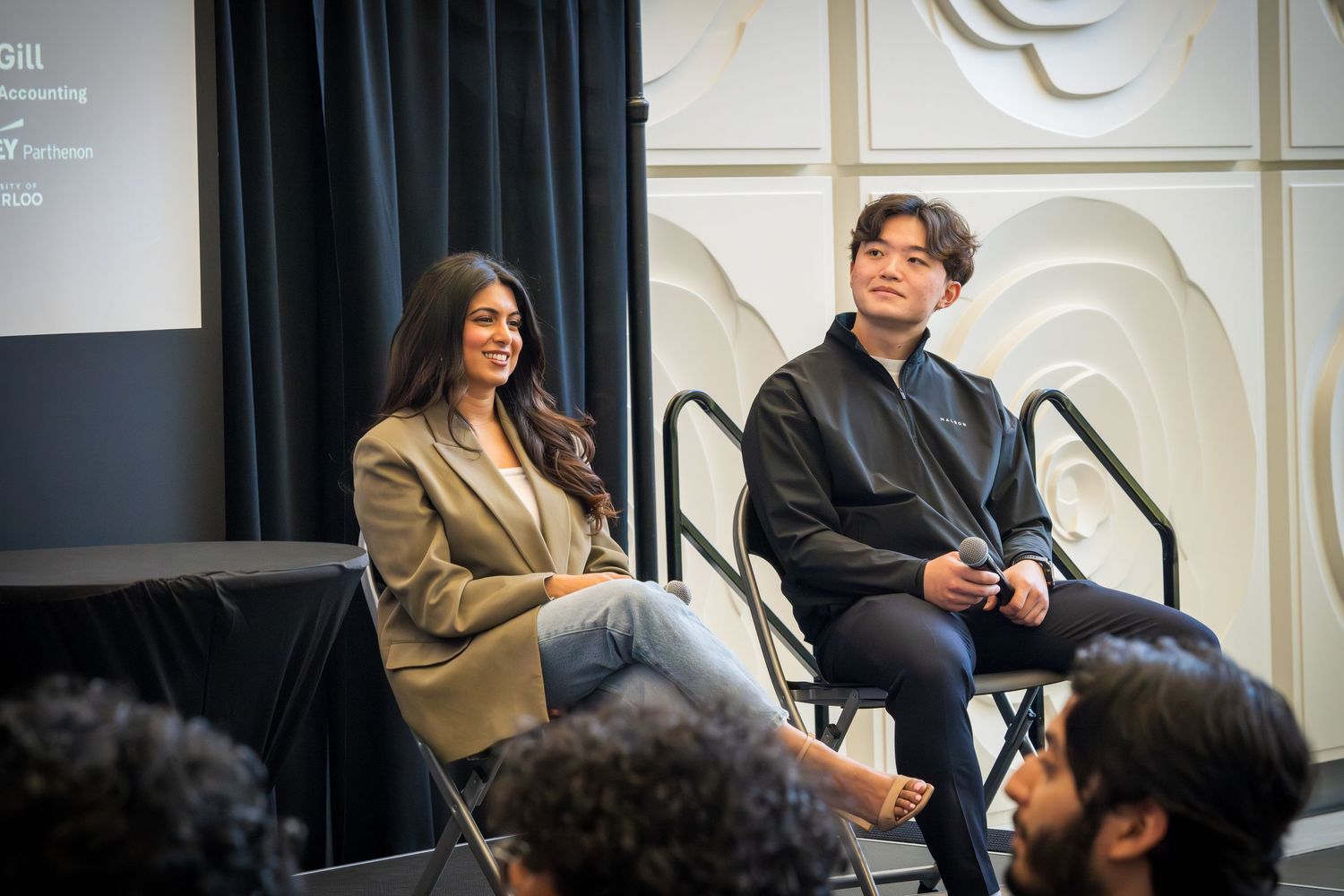 Professional panel discussion with speakers seated in casual business attire on stage.