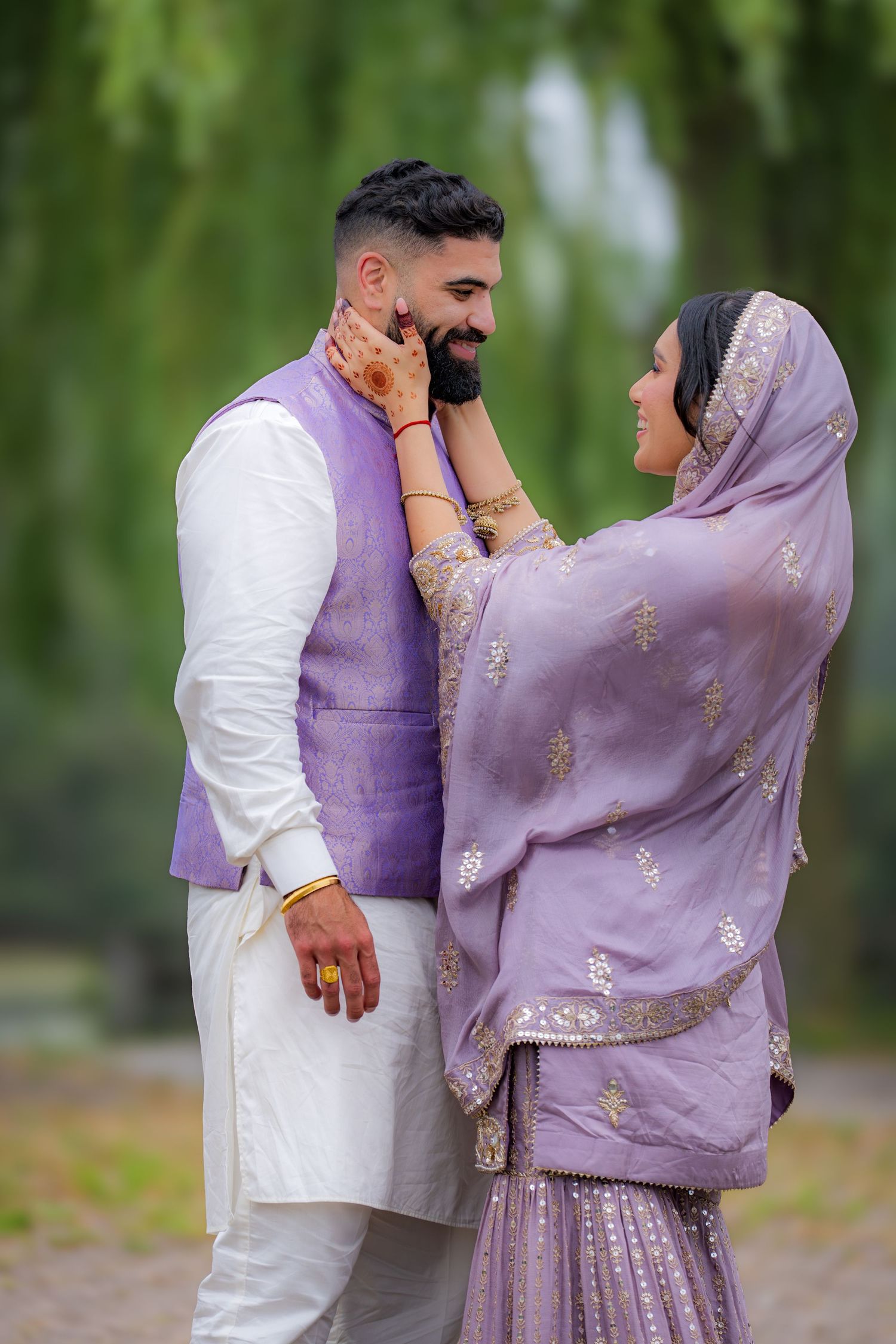A romantic moment captured between a couple in matching purple and white traditional South Asian attire.