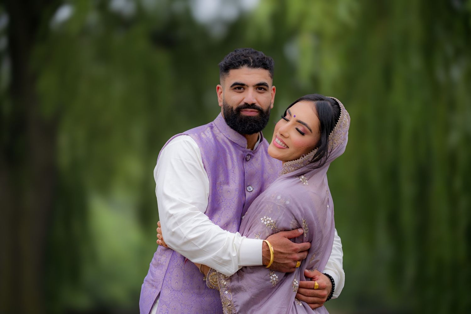 A couple shares an intimate embrace while wearing coordinated purple and white formal attire.