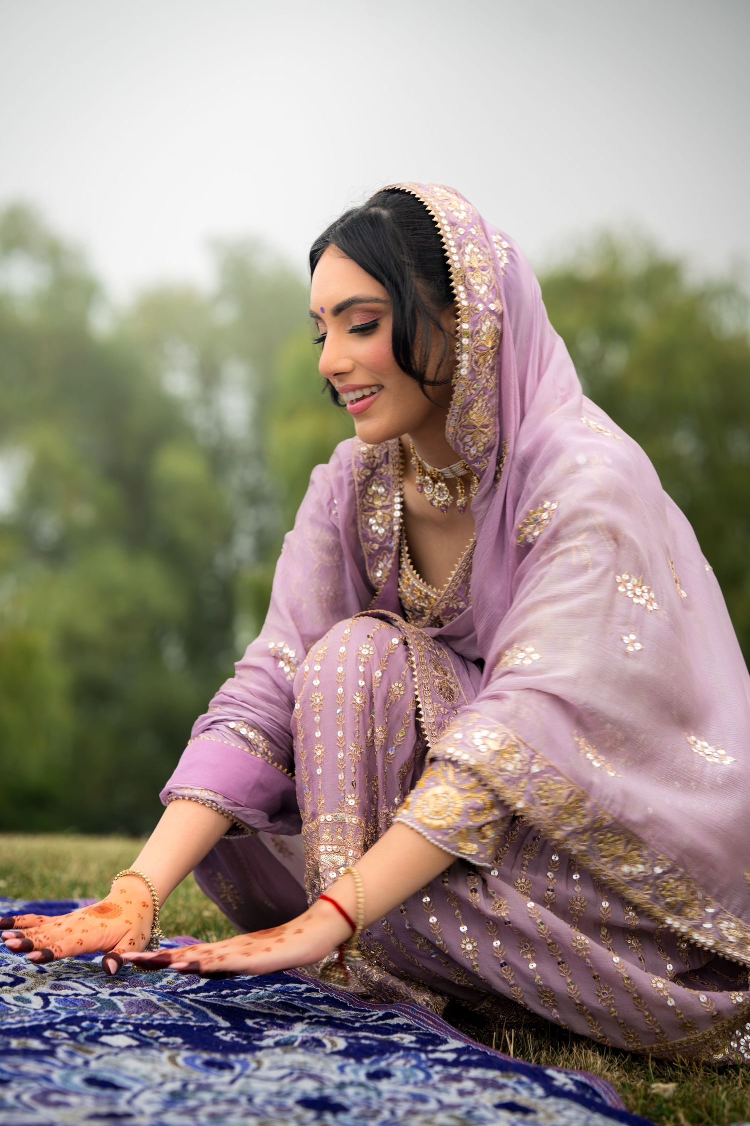 Traditional South Asian outfit in soft lavender with gold embellishments photographed outdoors.