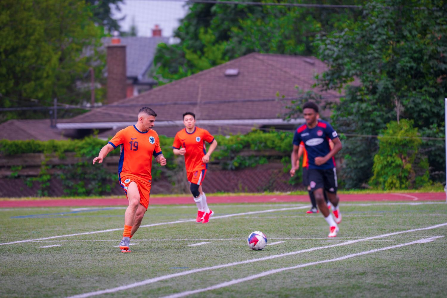 Soccer players compete for ball possession during a match on a grass field.