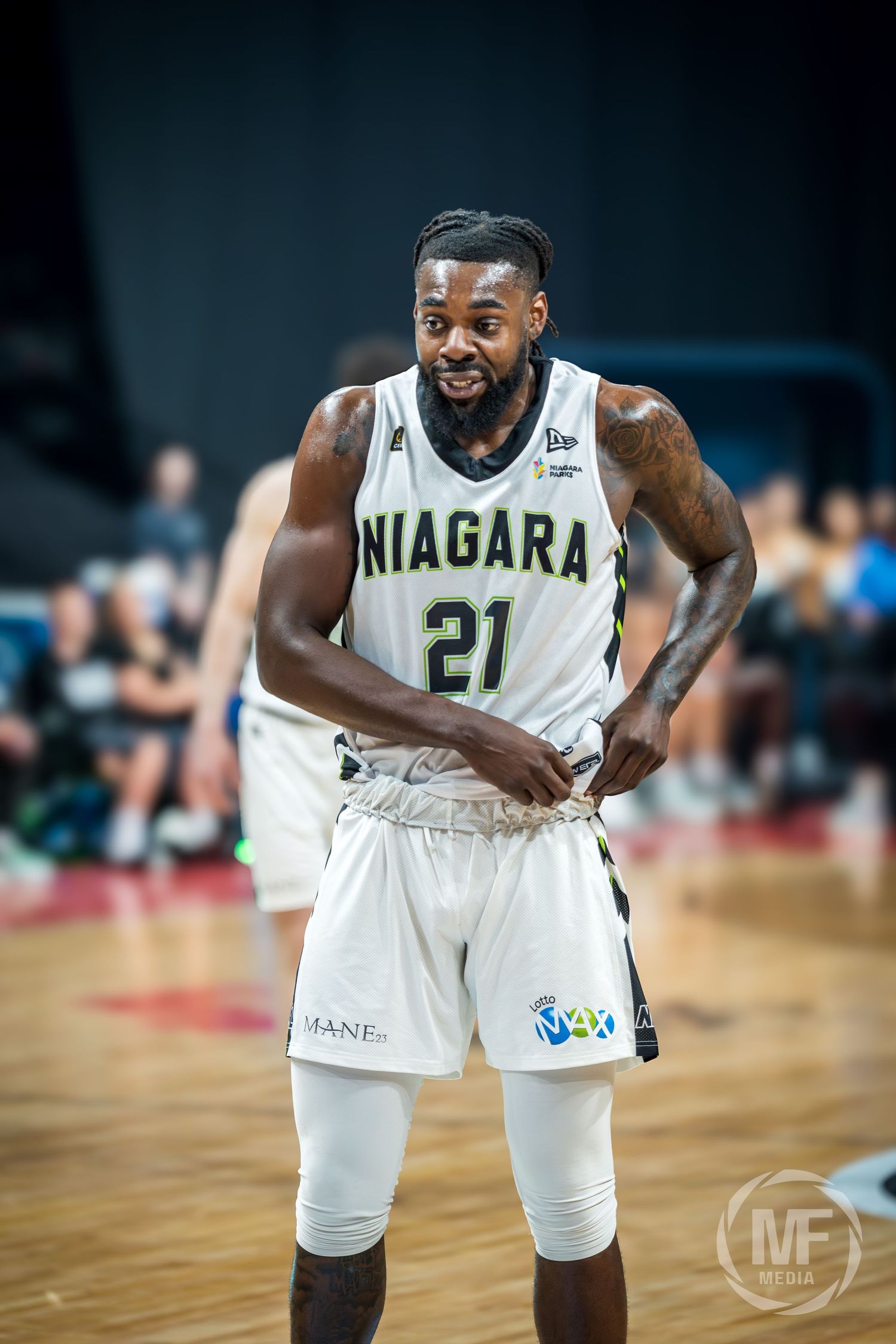 Niagara River Lions player #21 smiles on the court during a CEBL basketball game in white uniform.