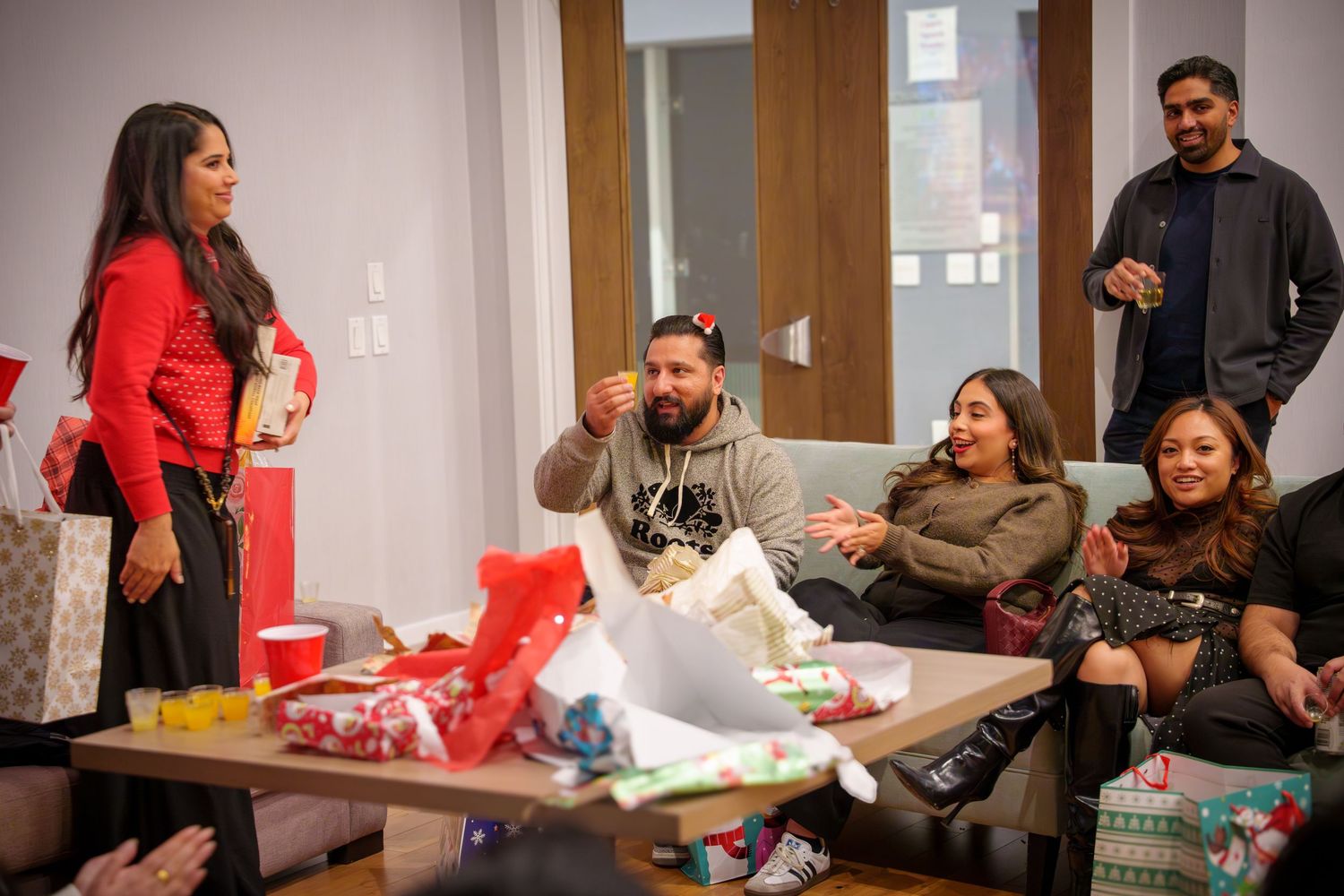 Group enjoying a festive party gathering in a bright indoor space with holiday decorations.
