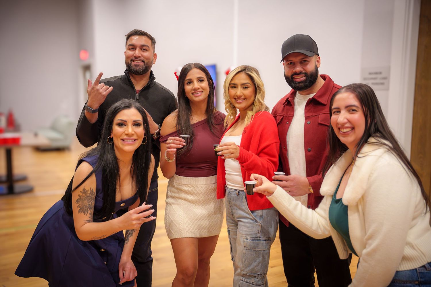 Group of people posing and gesturing at indoor social gathering.