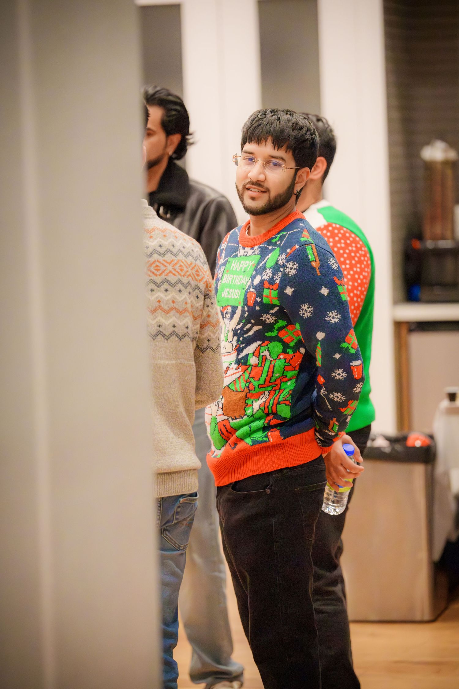 People wearing festive holiday sweaters at an indoor celebration.