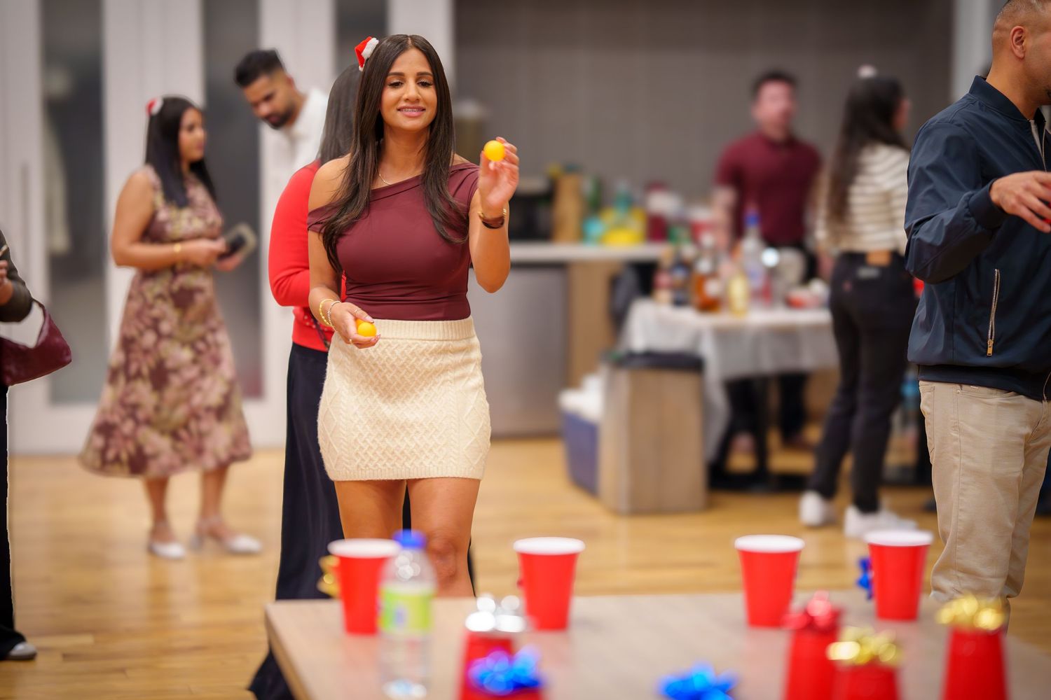 Social gathering with red cups arranged for party games on hardwood floor.