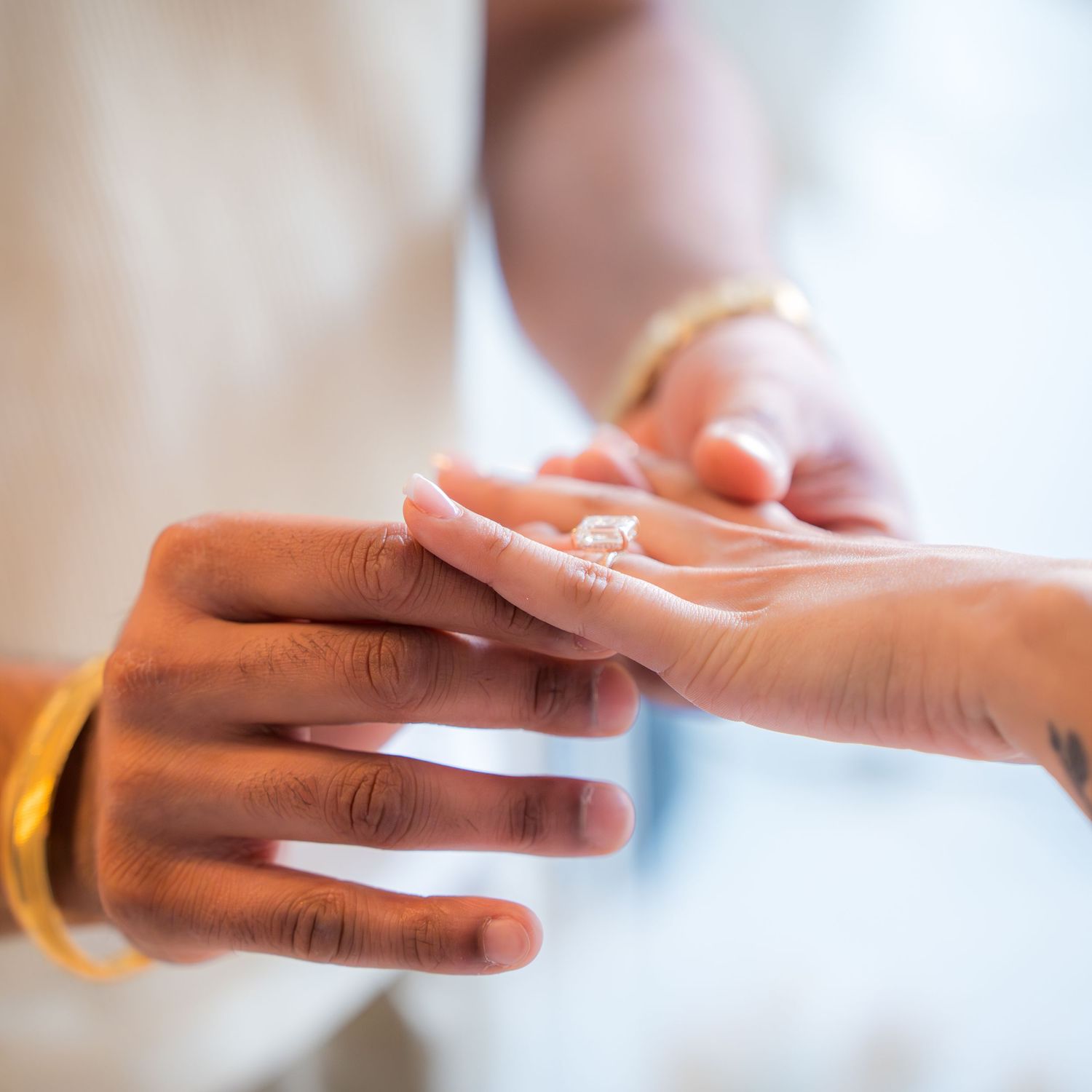 Close-up of a diamond engagement ring being placed on a womans finger during a proposal ceremony.
