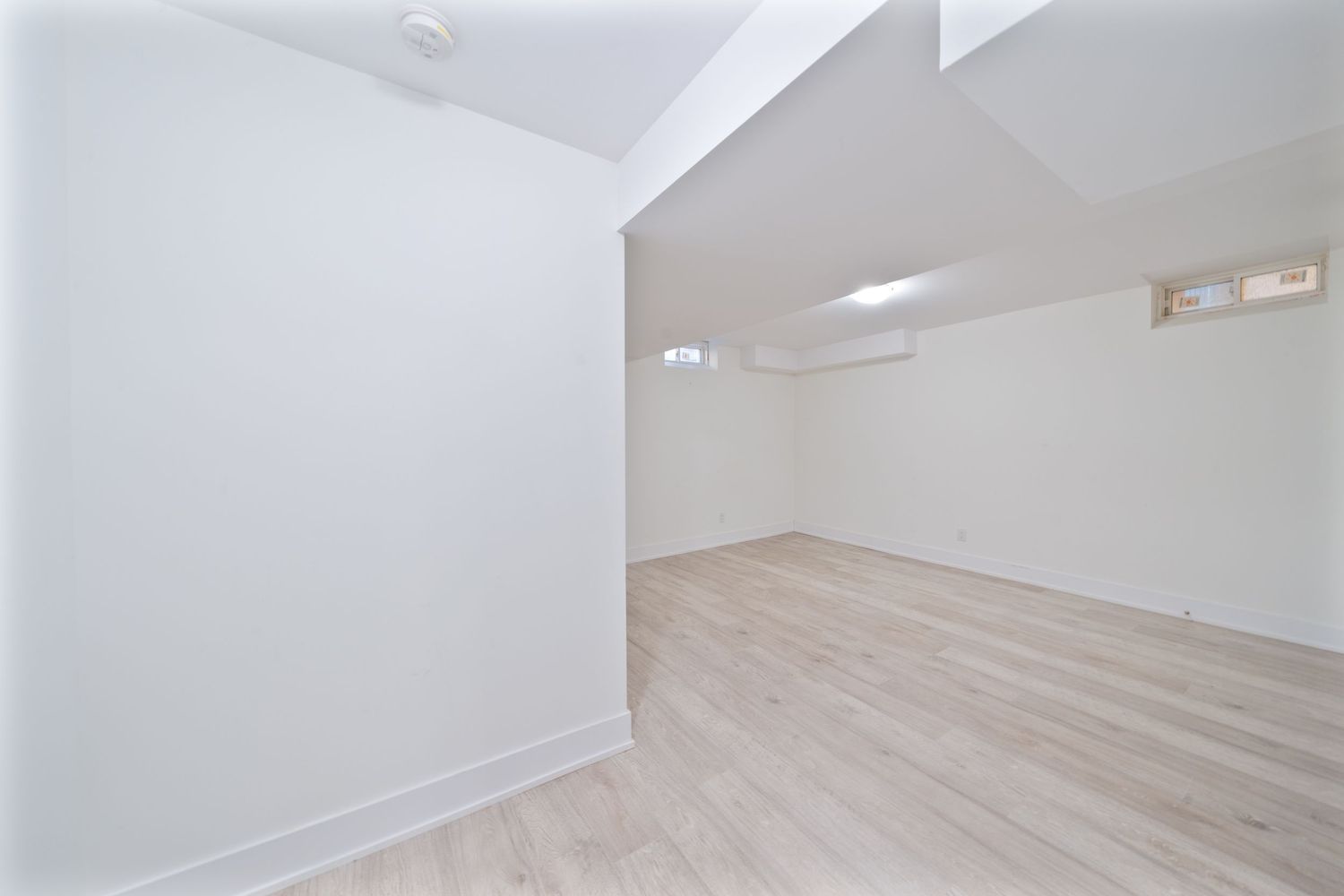 Modern white interior with light wood flooring and angled walls features a minimalist architectural design.