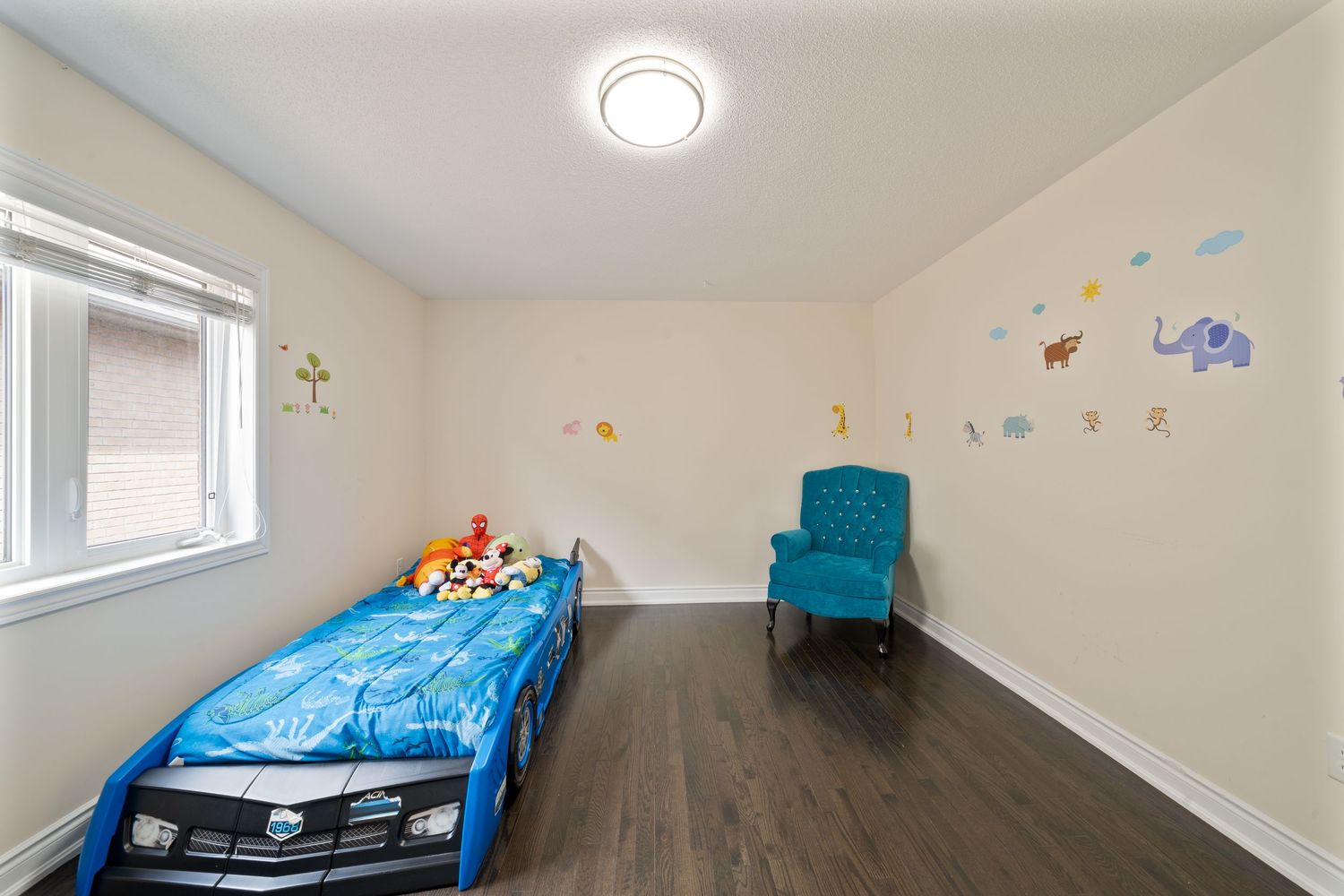 Large empty basement room with white walls, recessed lighting, and a blue accent chair in the corner.