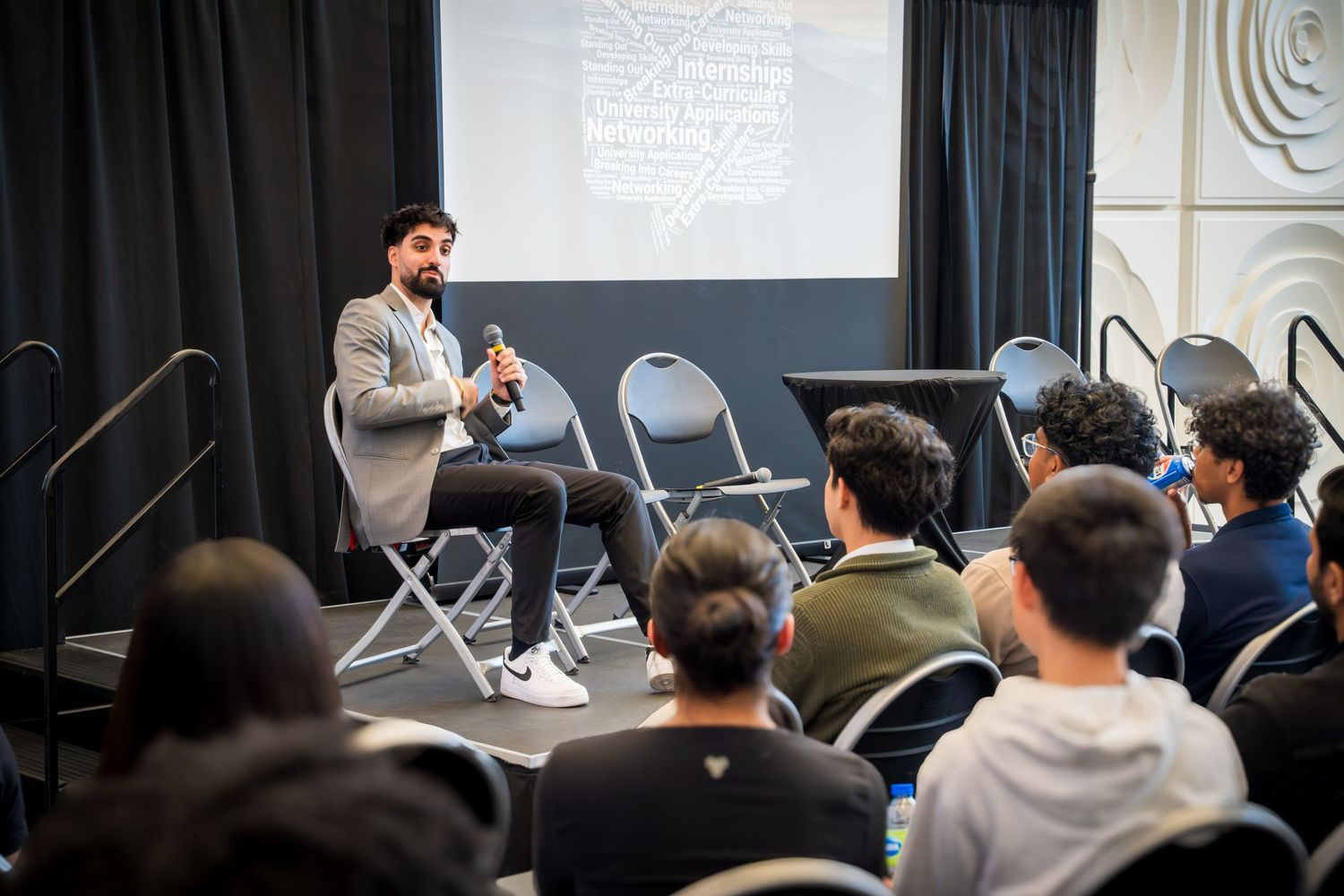 Audience members seated in rows listening attentively to a presentation in a modern conference room.