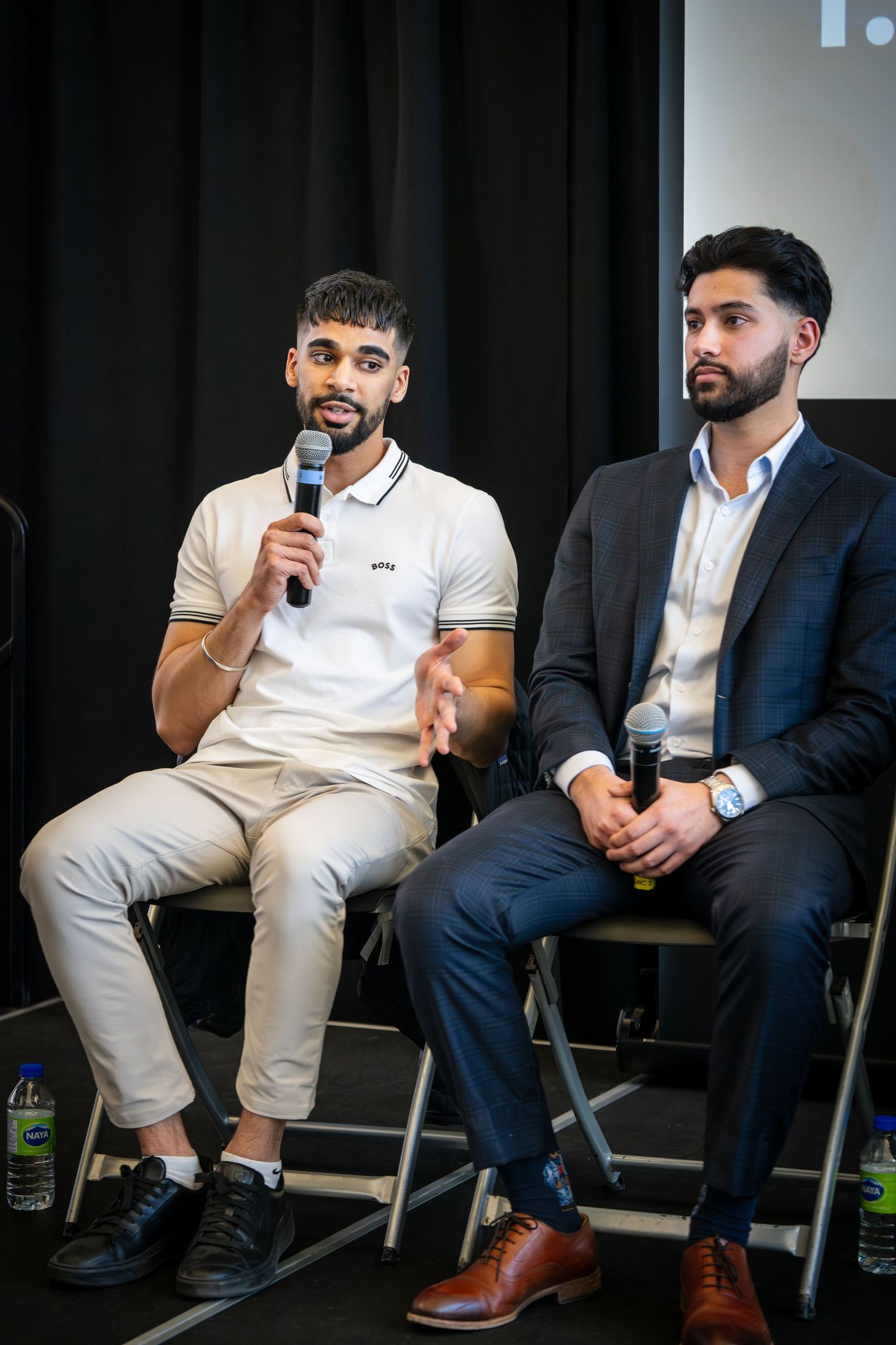 Speakers in business and casual attire participating in panel discussion on raised platform.