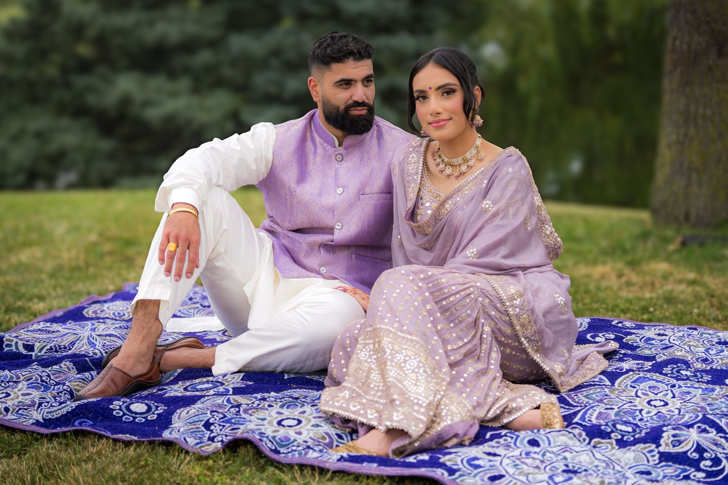 Couple shares tender moments during outdoor photo session on blue and white patterned blanket.