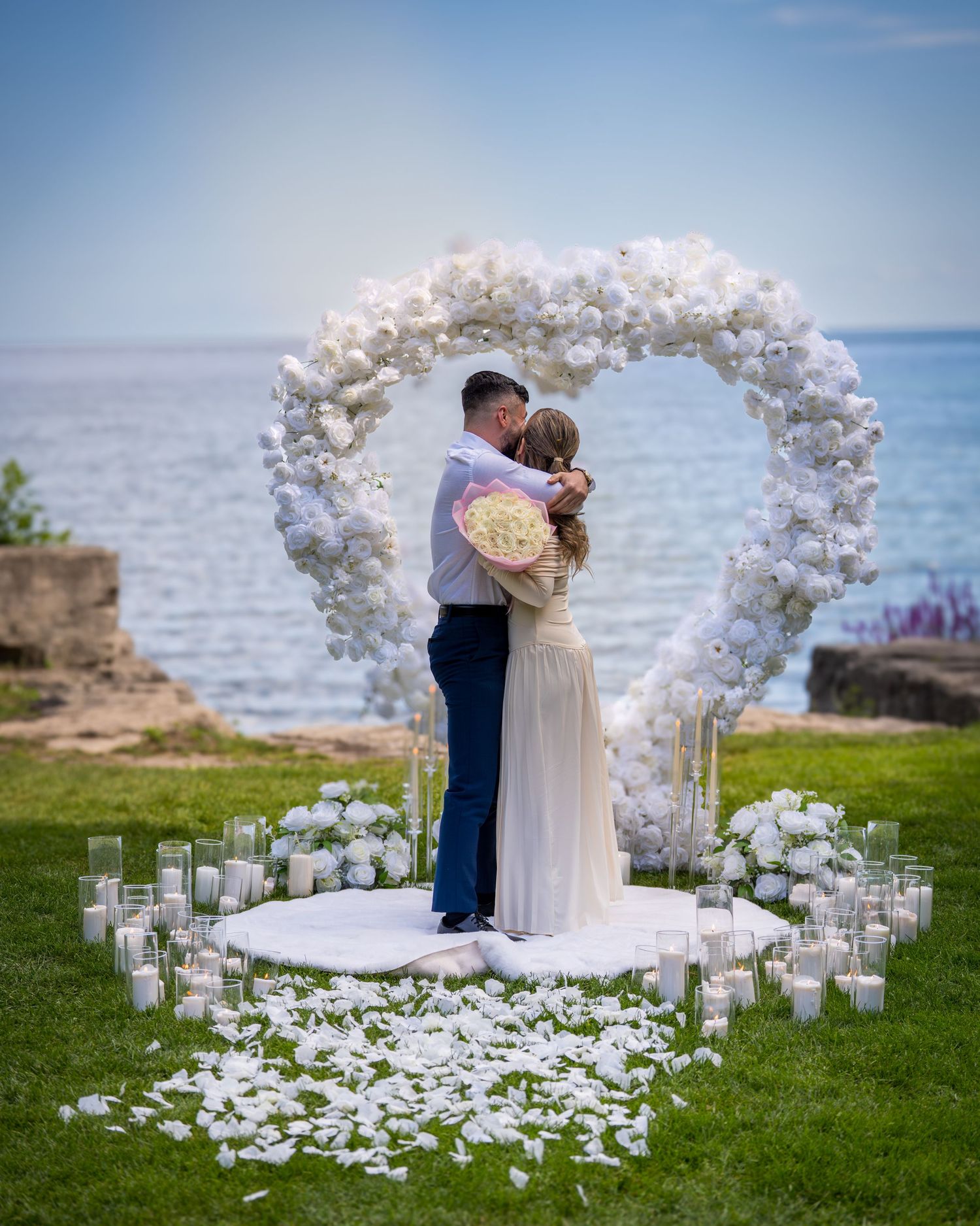 Wedding ceremony moment under white balloon arch by scenic waterfront.