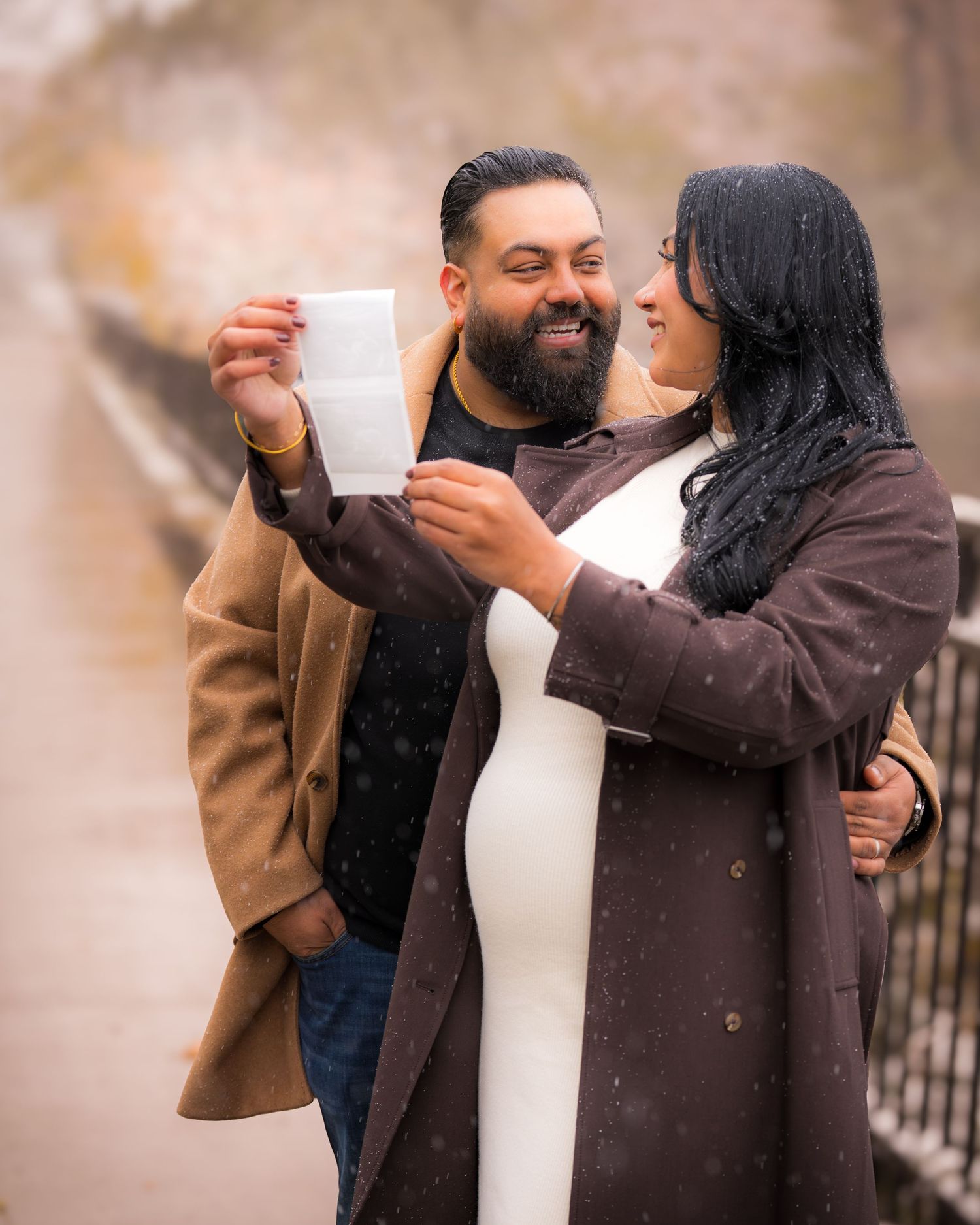 Couple sharing warm drinks outdoors on a snowy winter day while dressed in cozy coats.