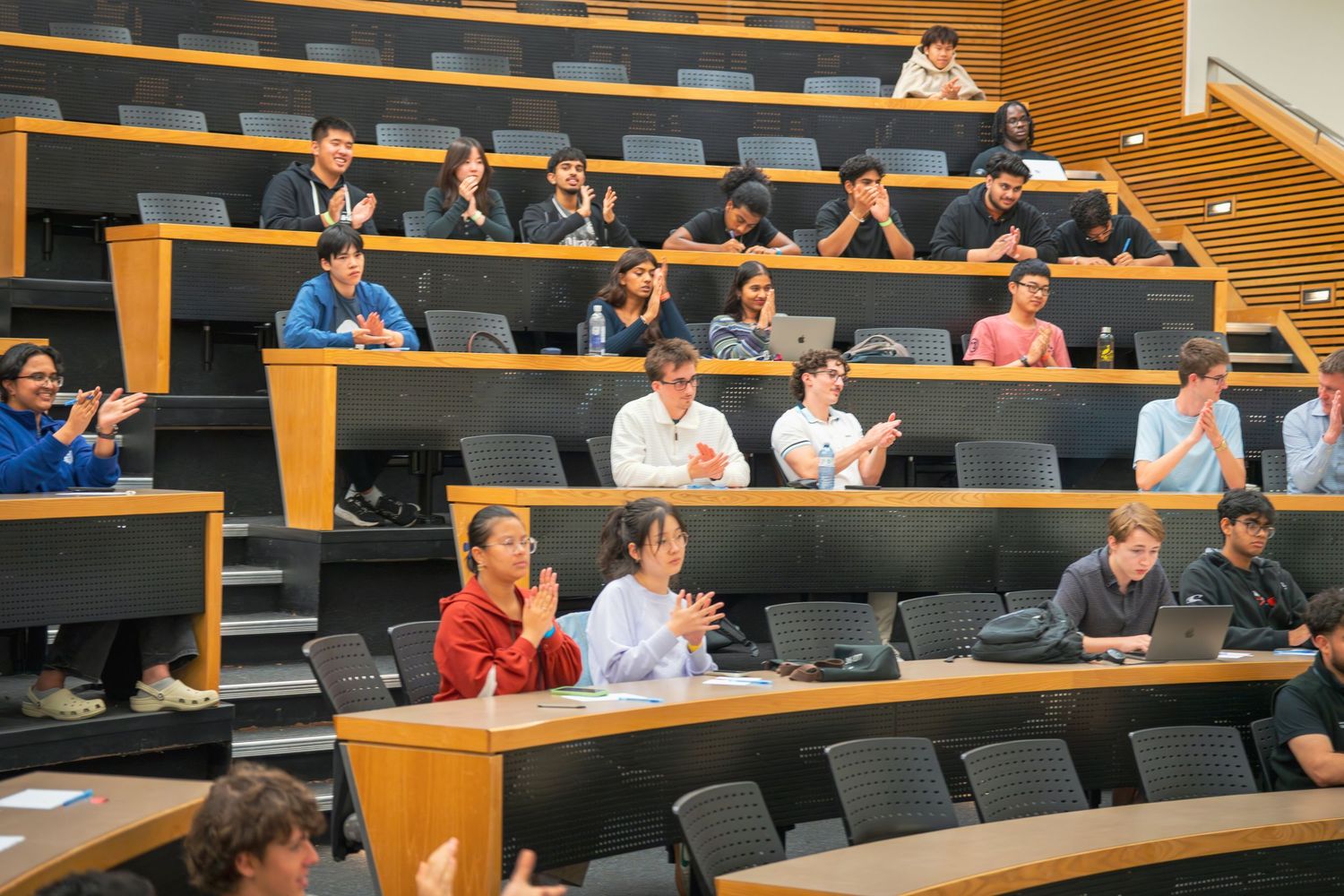 Audience members seated in tiered lecture hall rows during presentation or discussion.