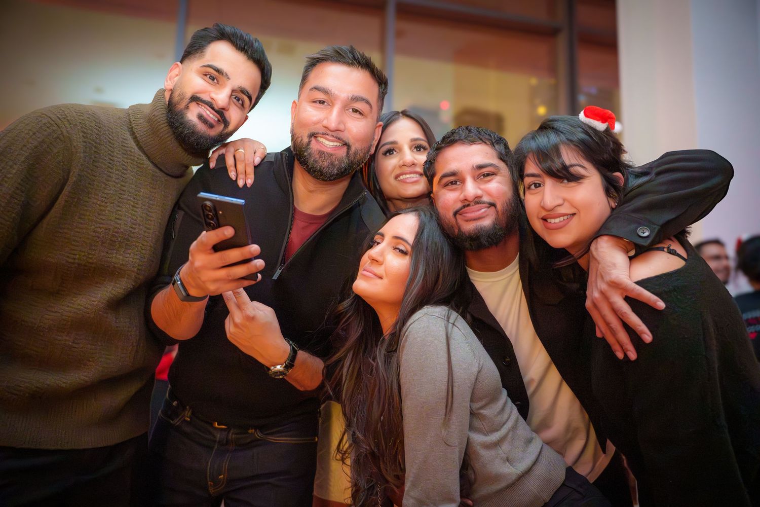 Friends gathered close together smiling and posing at a holiday party.