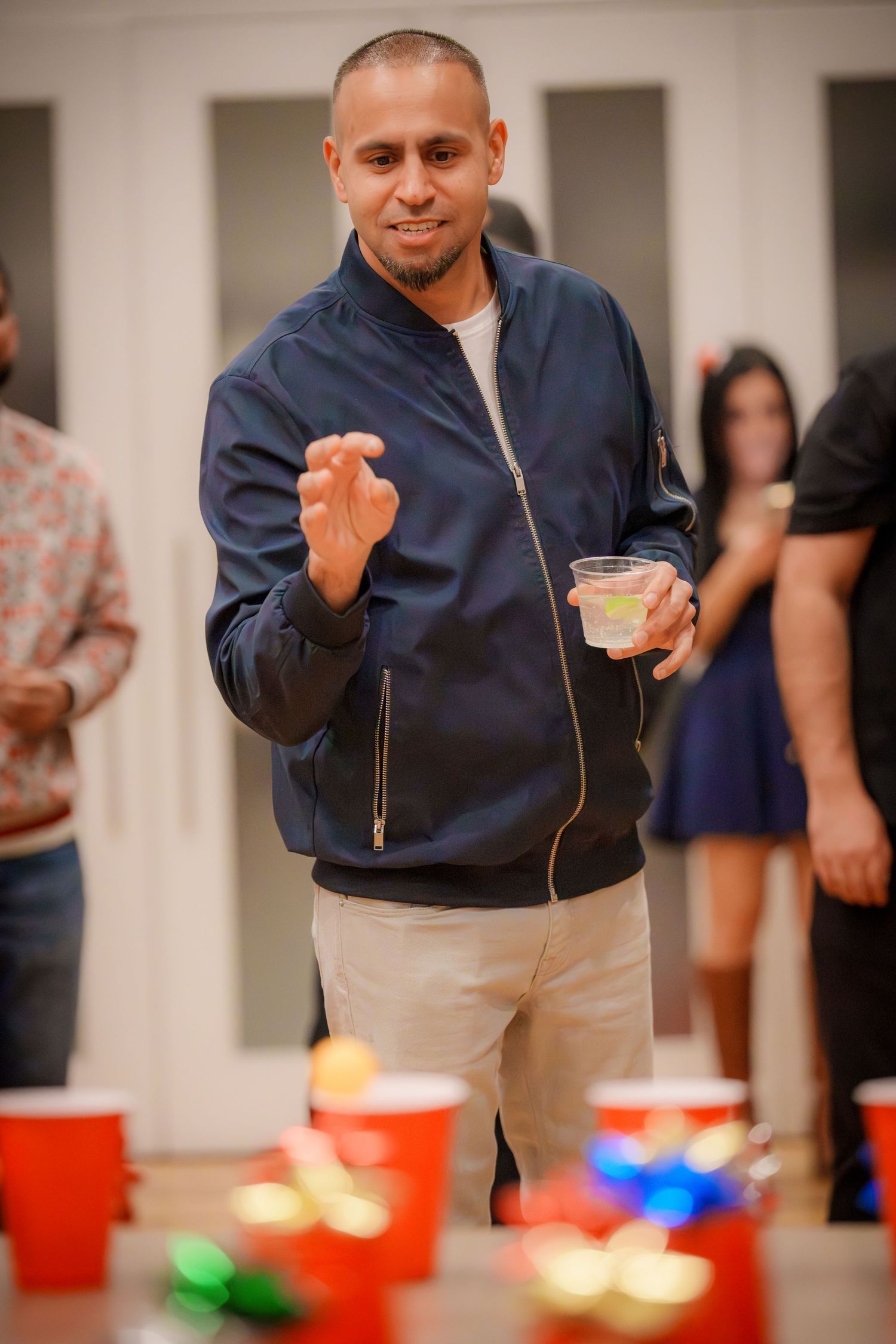 People gathered around red cups playing a party game on a white table.