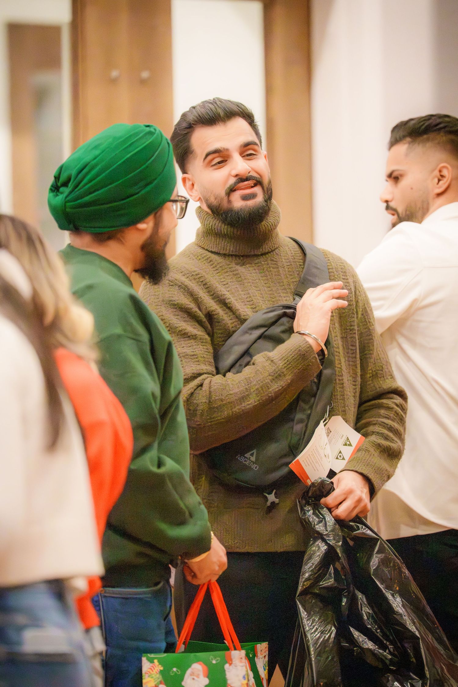 People in casual wear and traditional headwear interacting at a social gathering.