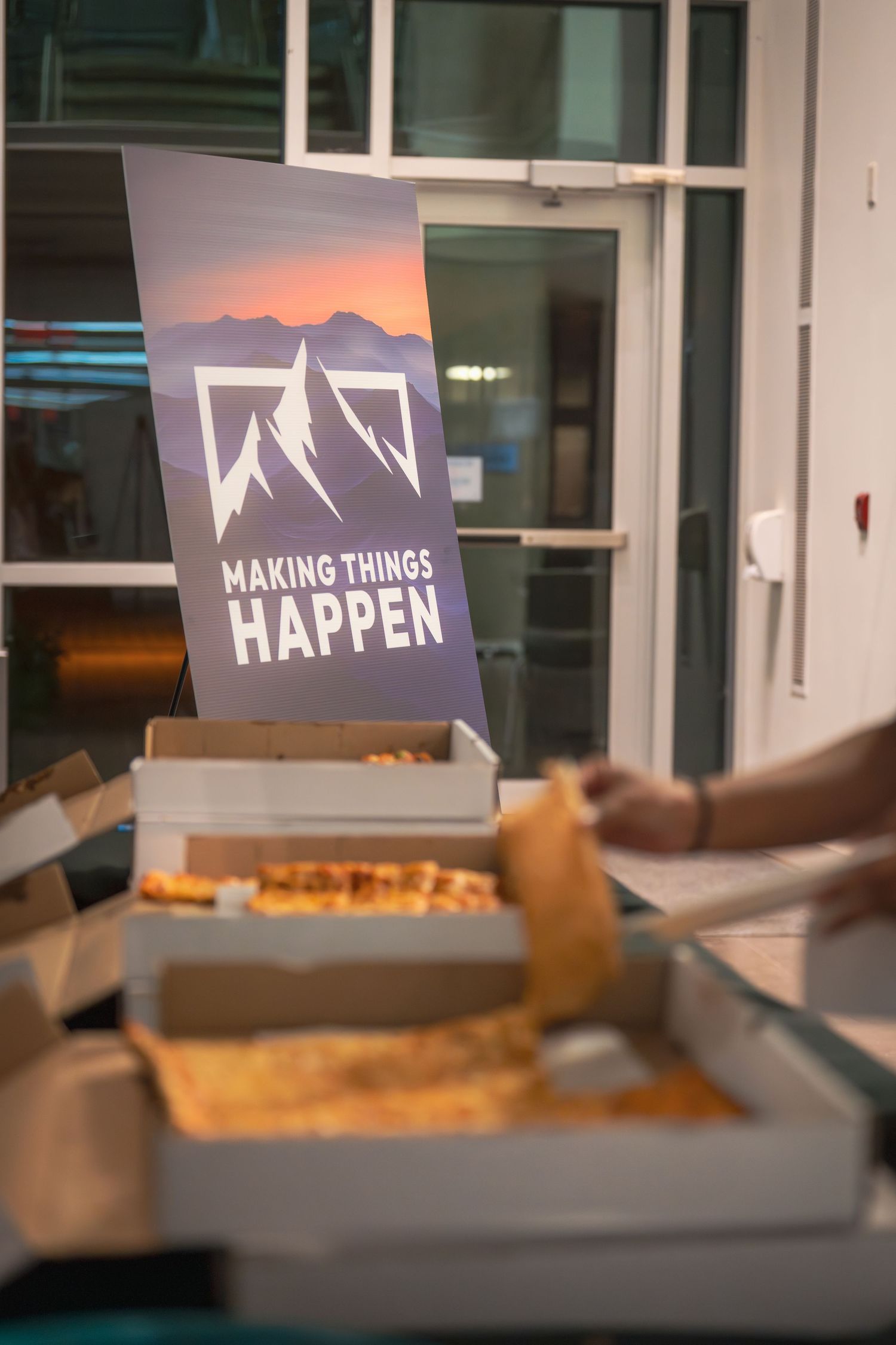 'Making Things Happen' banner displayed near pizza boxes at an event.