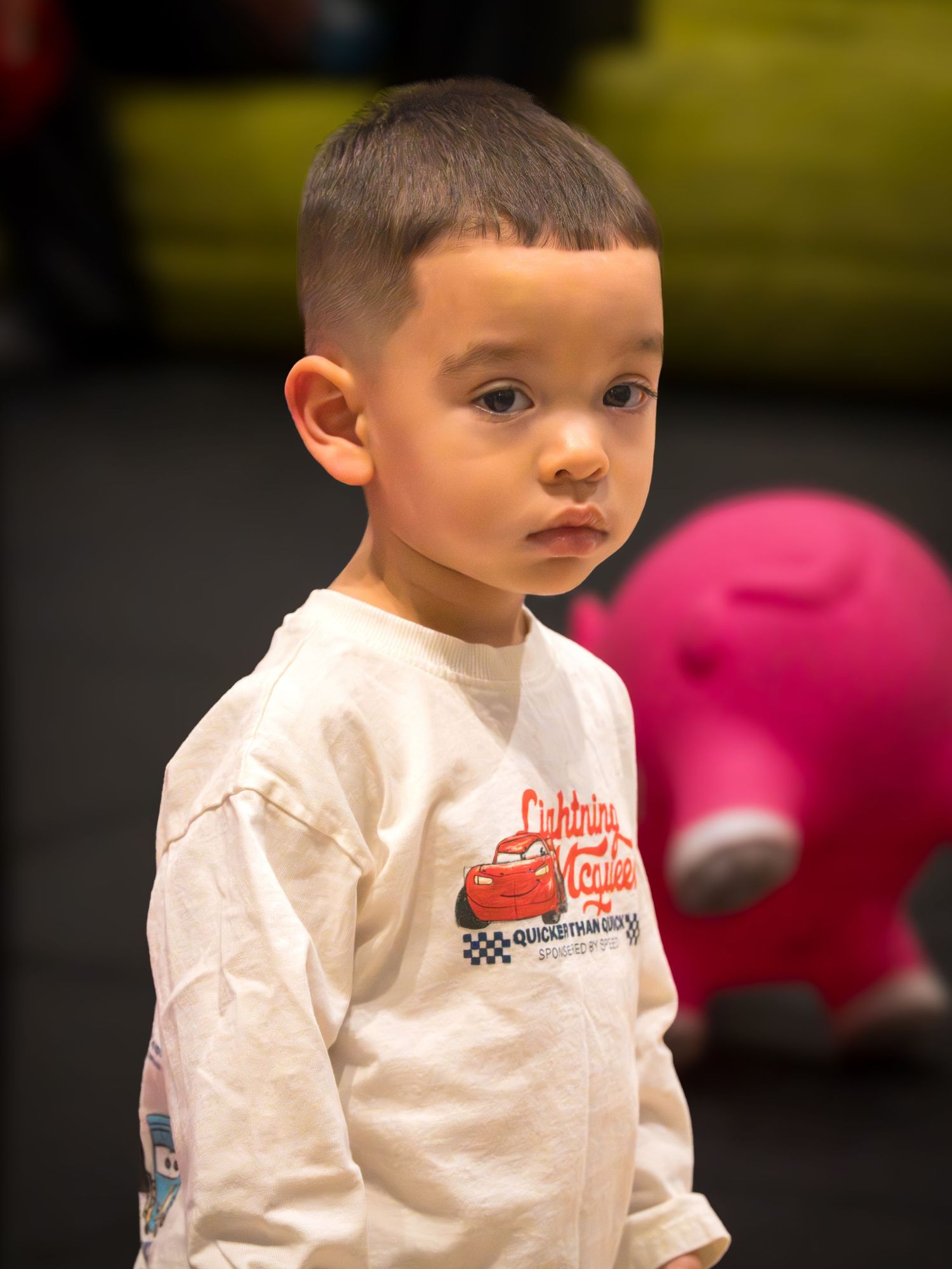 Young boy wearing a Lightning McQueen shirt looking over his shoulder at a Cars themed birthday party.