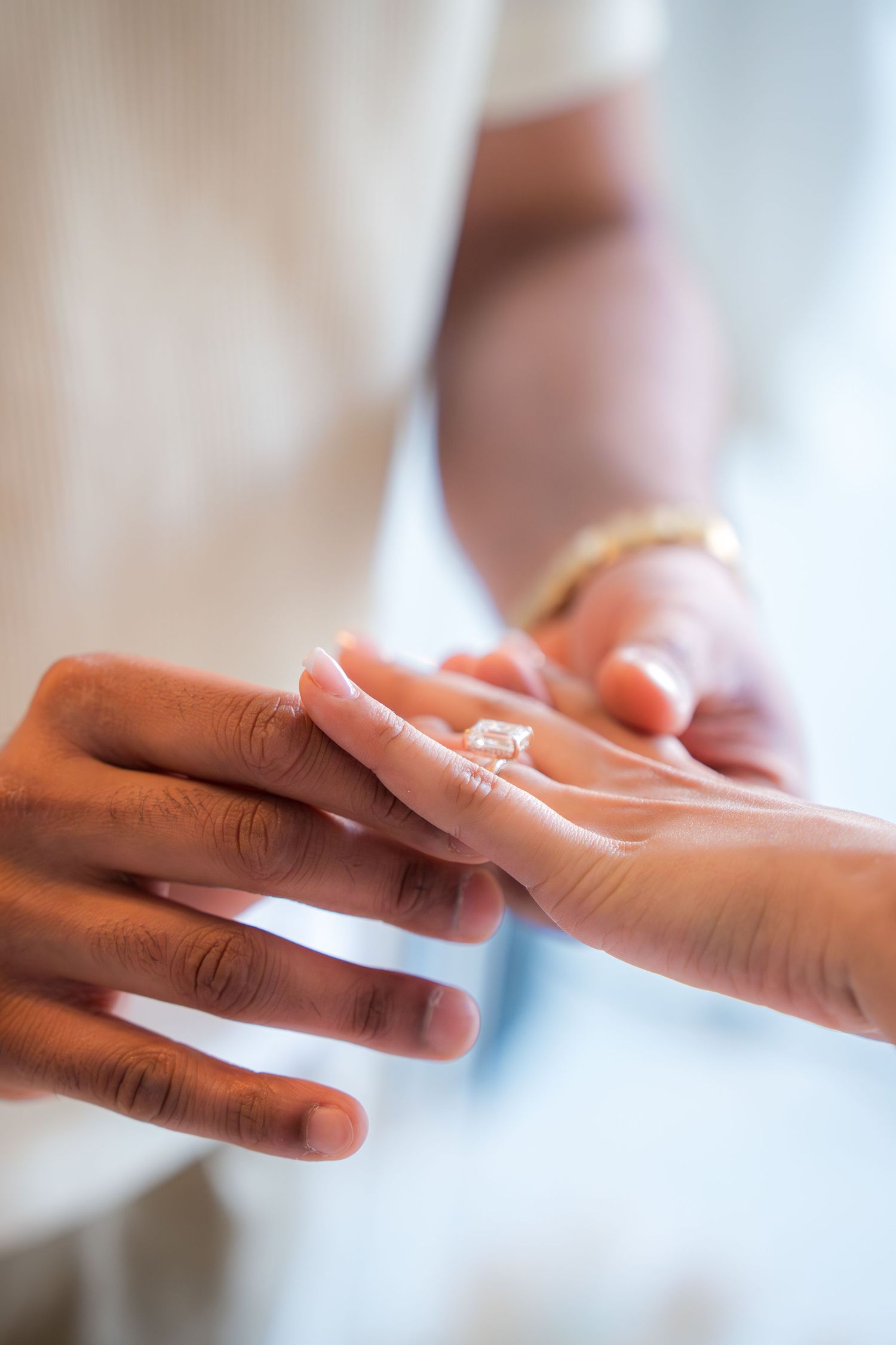 Close-up of man placing diamond engagement ring on womans finger during proposal.