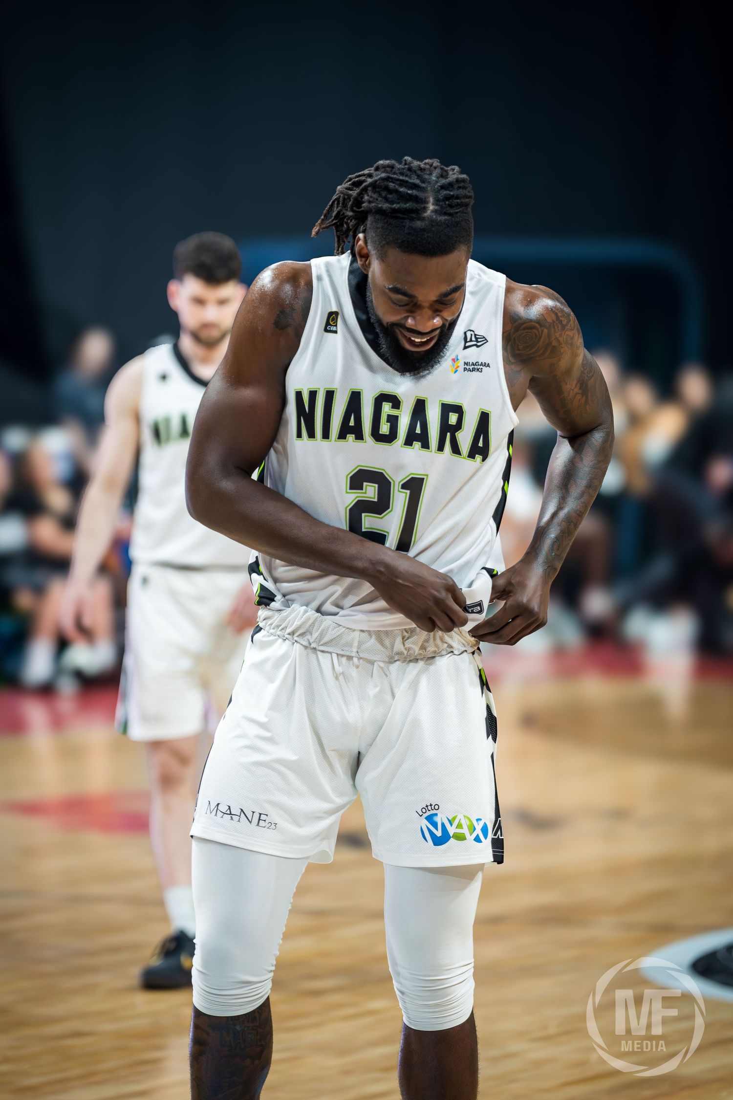 Niagara basketball player number 21 smiles while adjusting uniform on court.