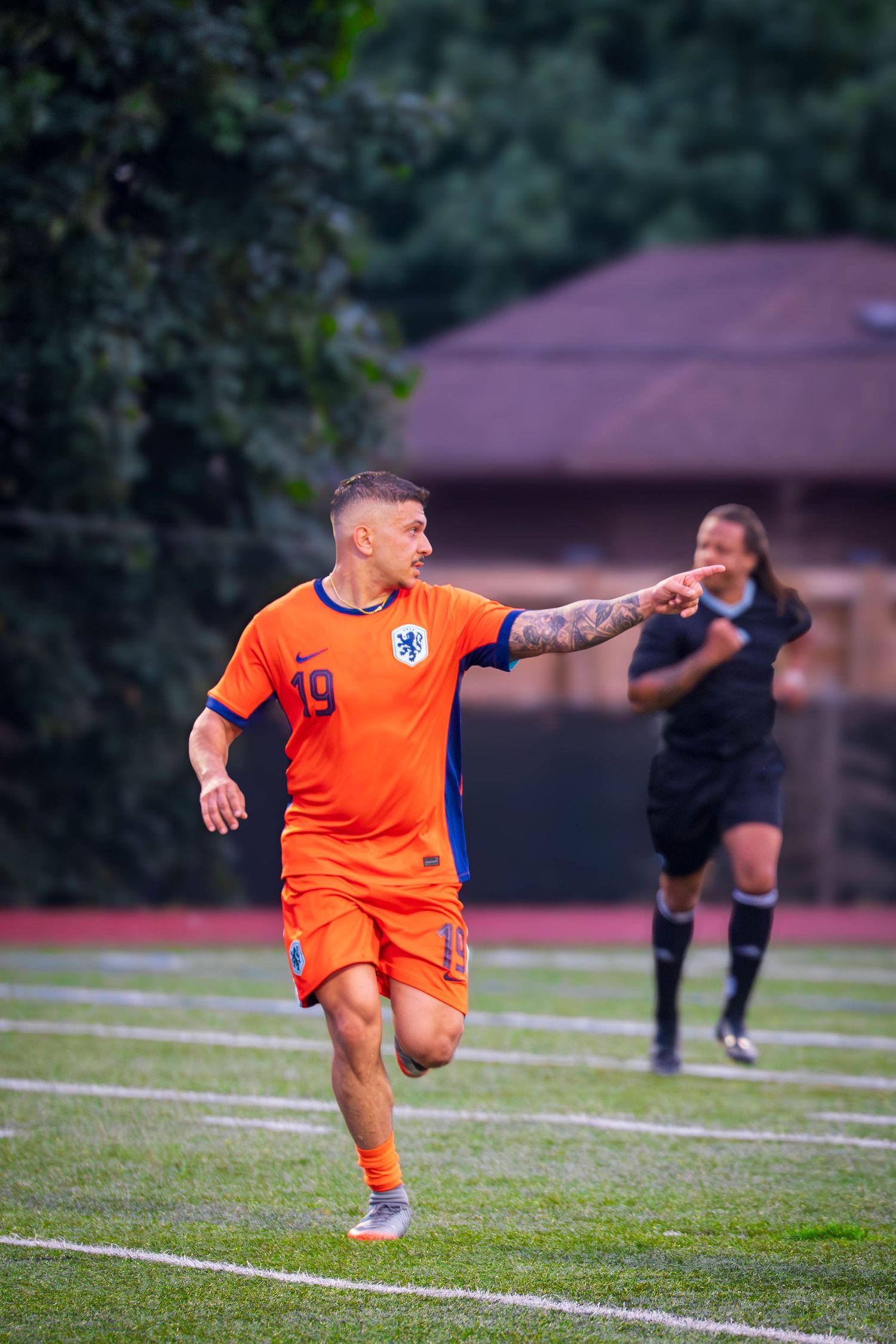 A player in orange stretches for the ball during an intense soccer match.
