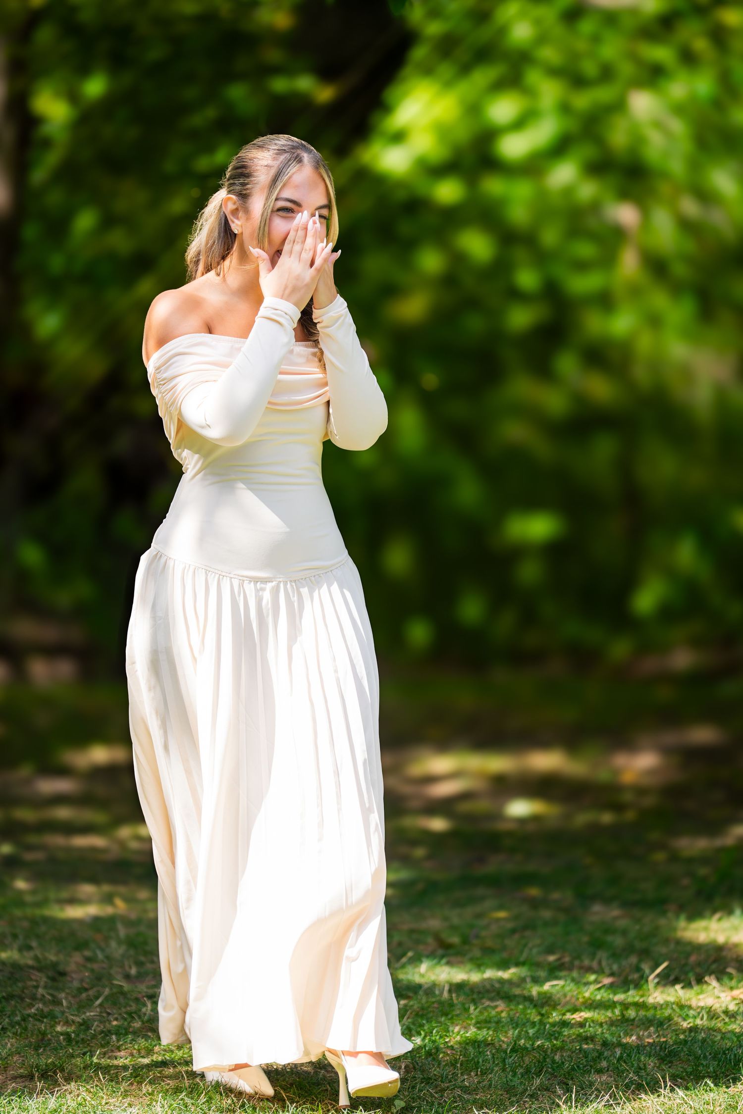 A flowing white wedding dress captured in motion against a lush green outdoor background.