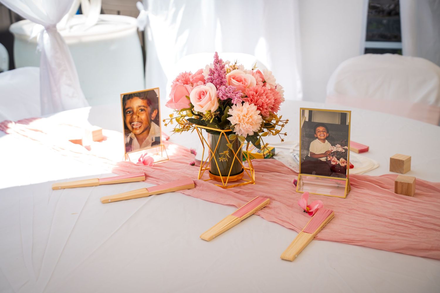 Baby shower table decorated with pink runners, flowers, and activity materials.